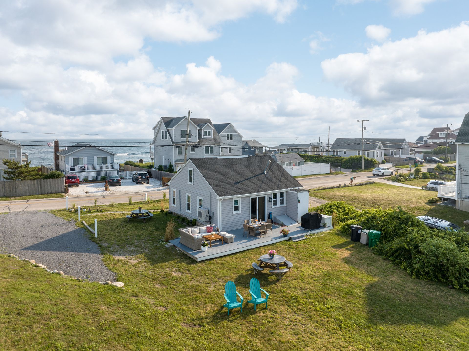 An aerial view of a small white house with blue chairs in front of it.
