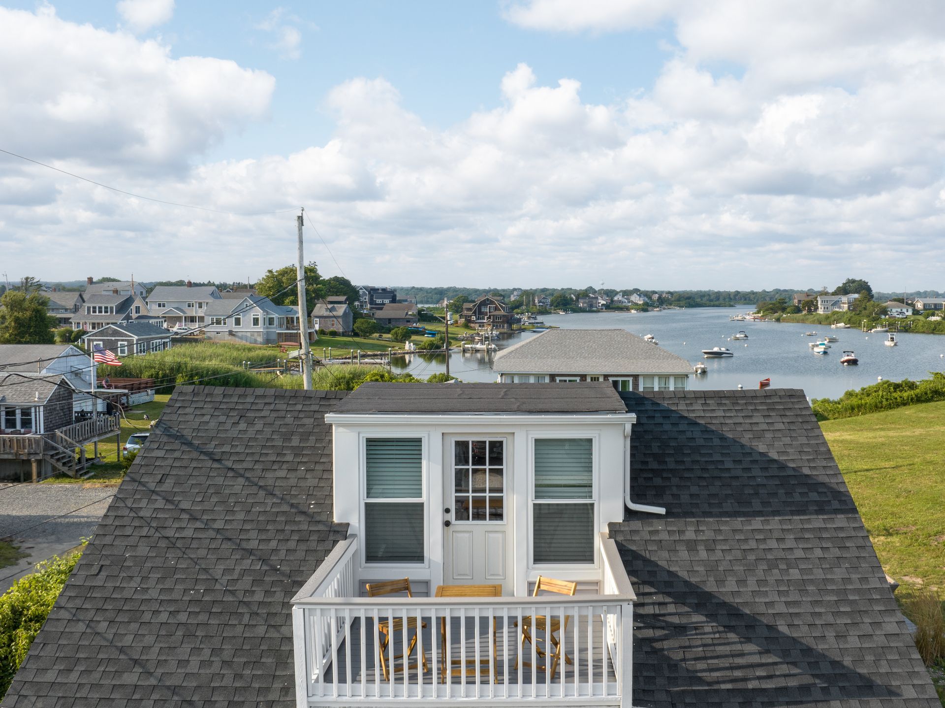 An aerial view of a house with a balcony overlooking a body of water.