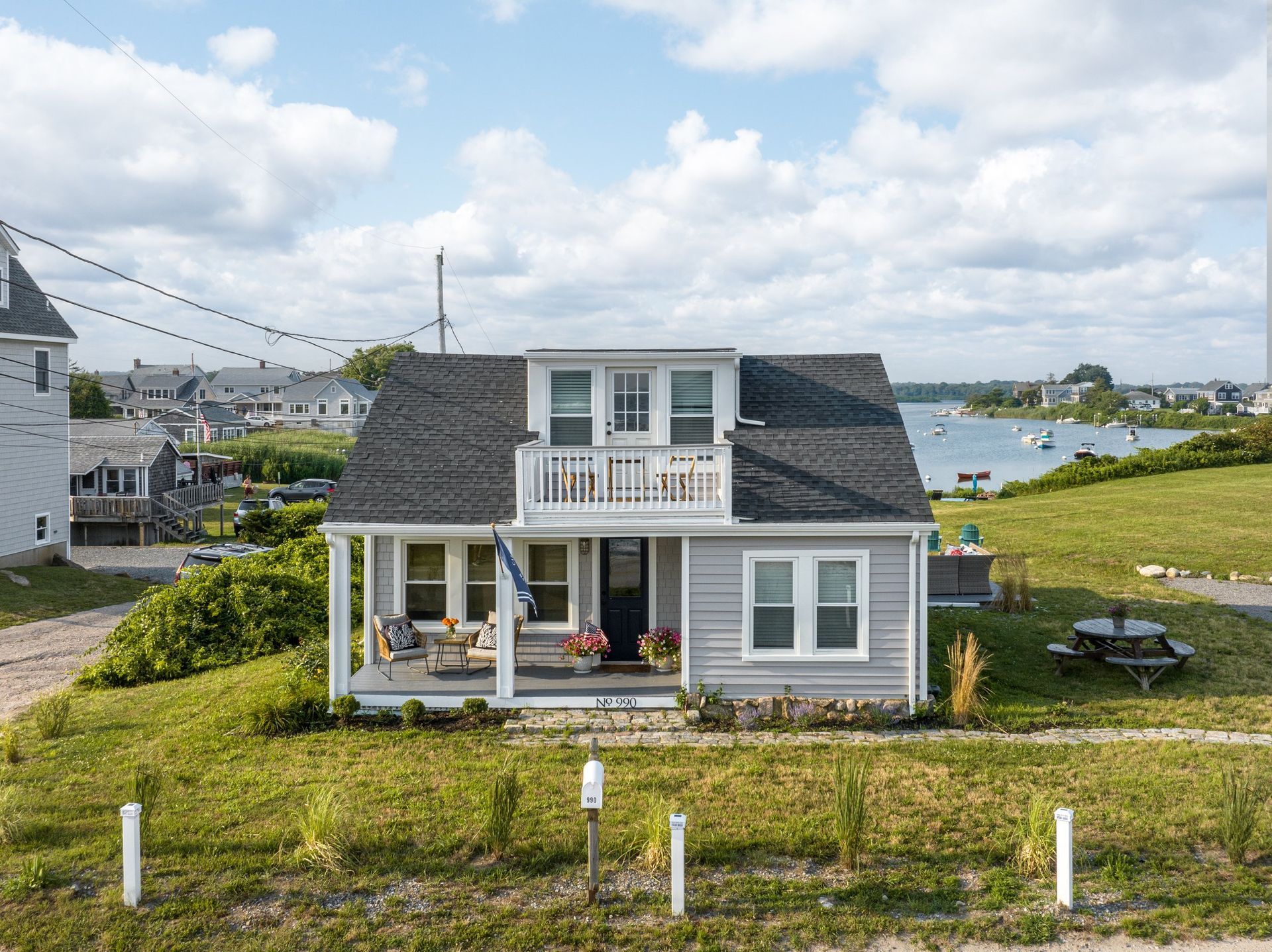 An aerial view of a house on a hill overlooking a body of water.