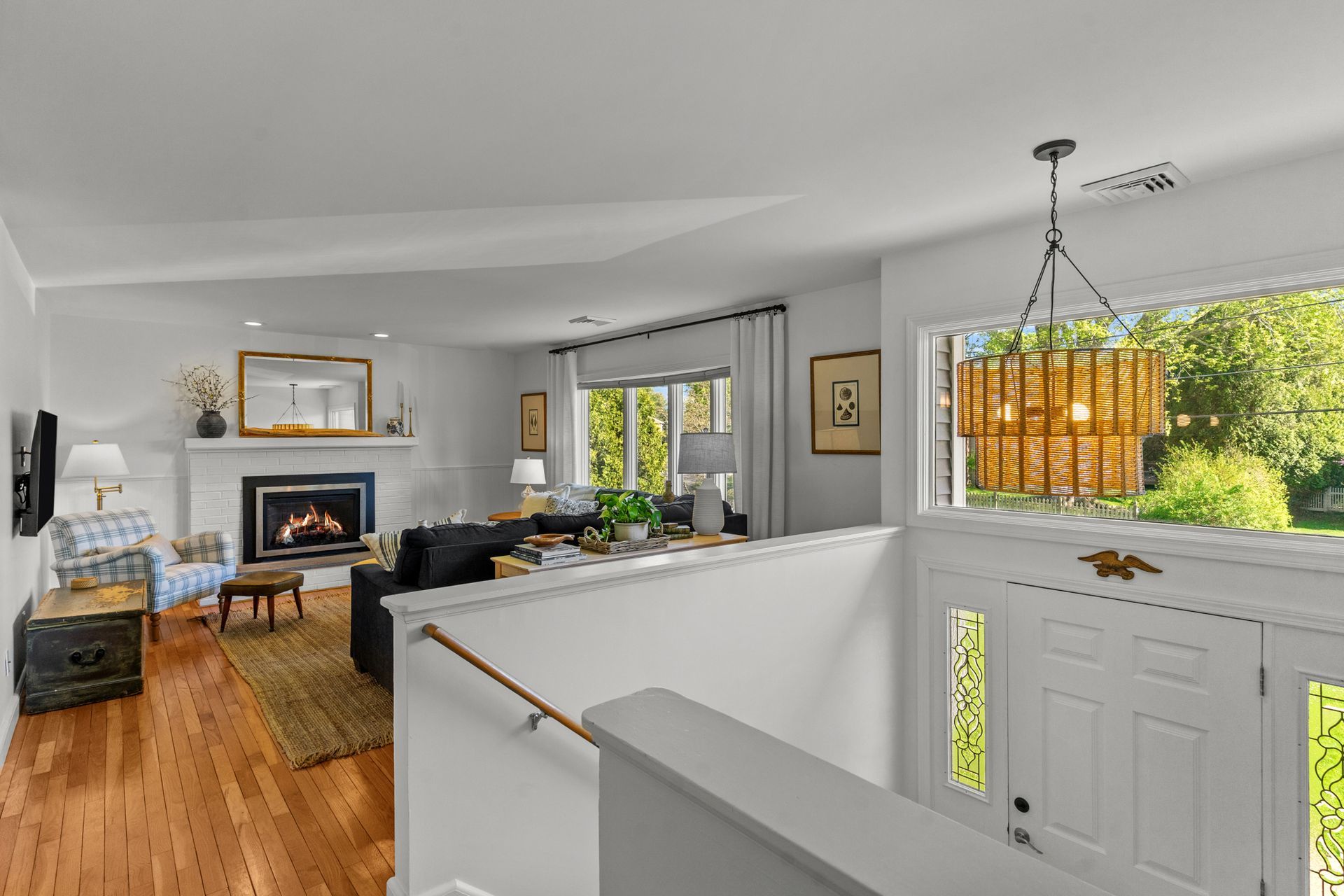A living room with hardwood floors , a fireplace and a chandelier.