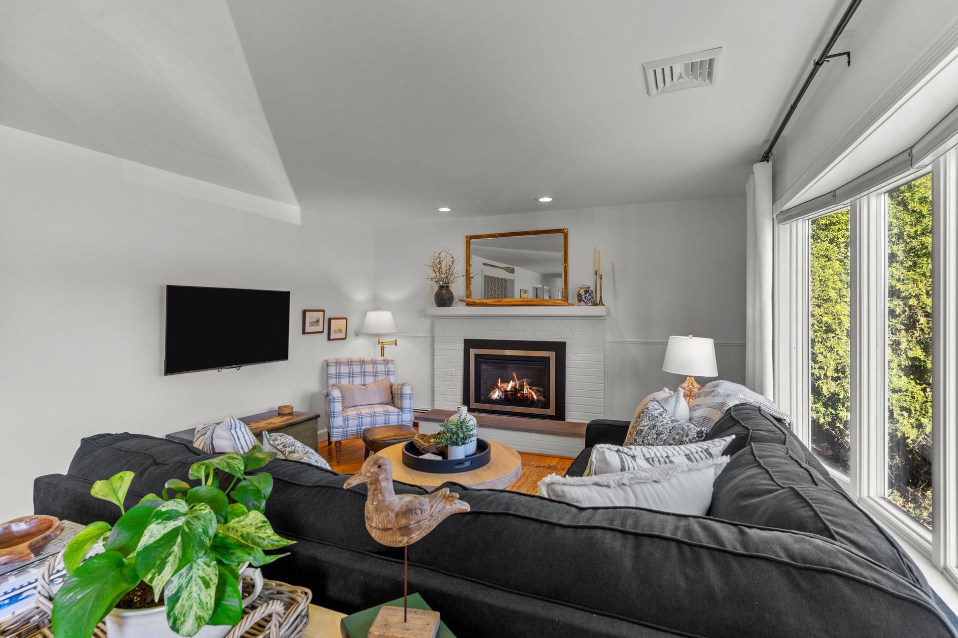 A living room with a couch , chairs , a fireplace and a flat screen tv.
