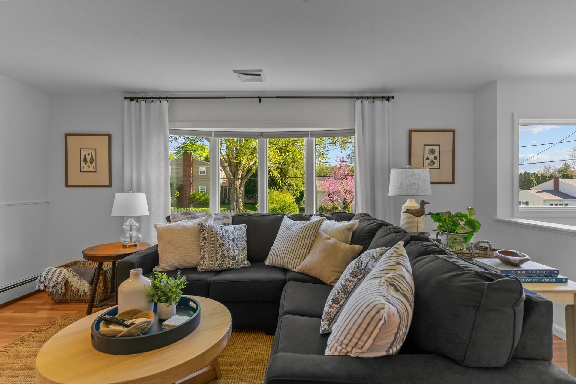 A living room with a couch , coffee table , lamps and a large window.