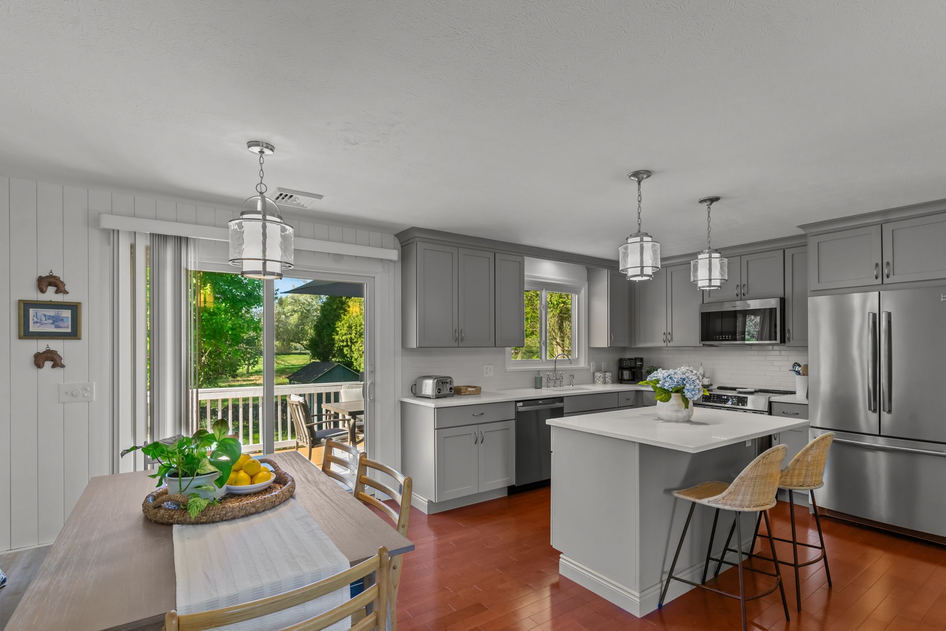 A kitchen with stainless steel appliances , a large island , a table and chairs.