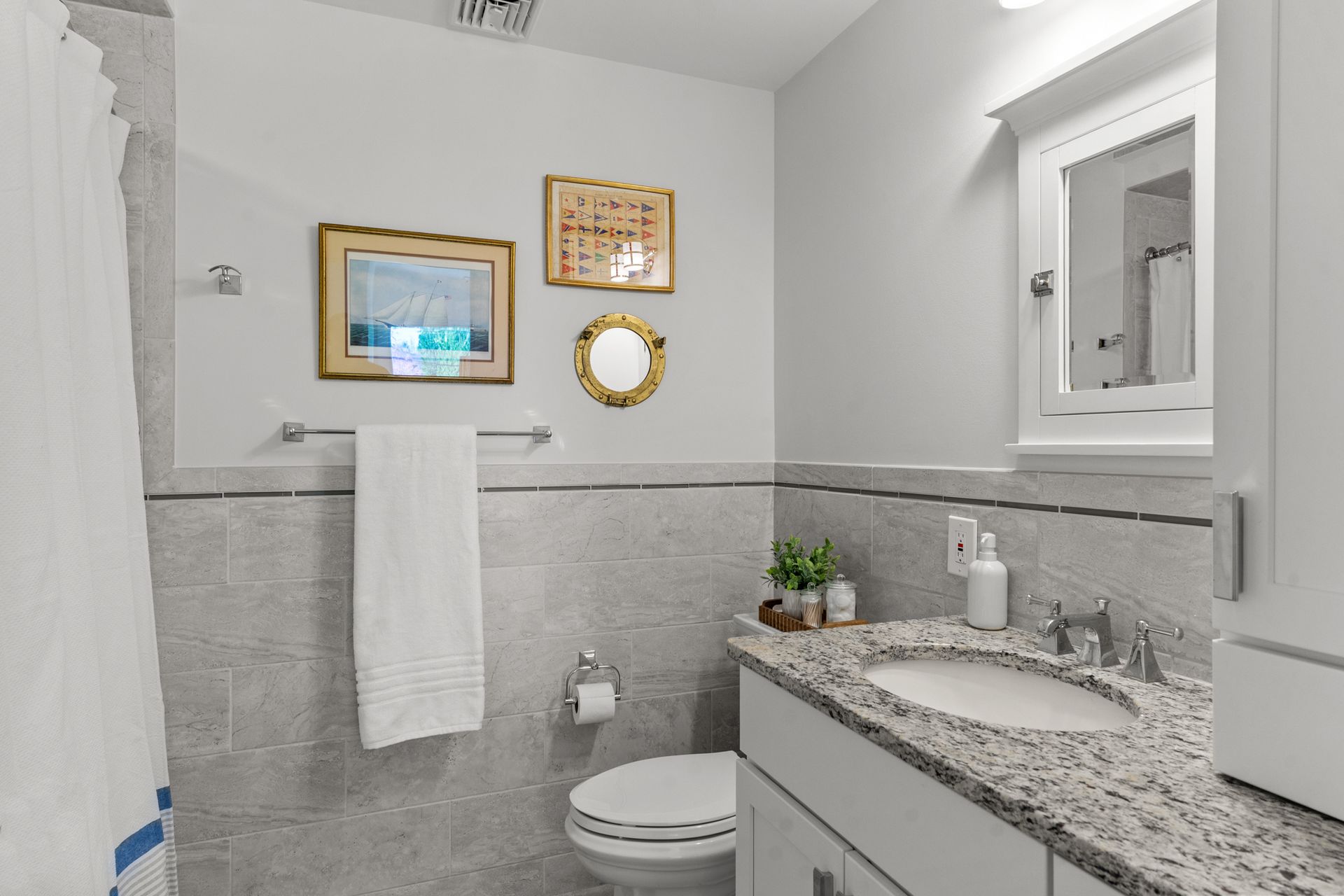A bathroom with a toilet , sink , mirror and shower curtain.
