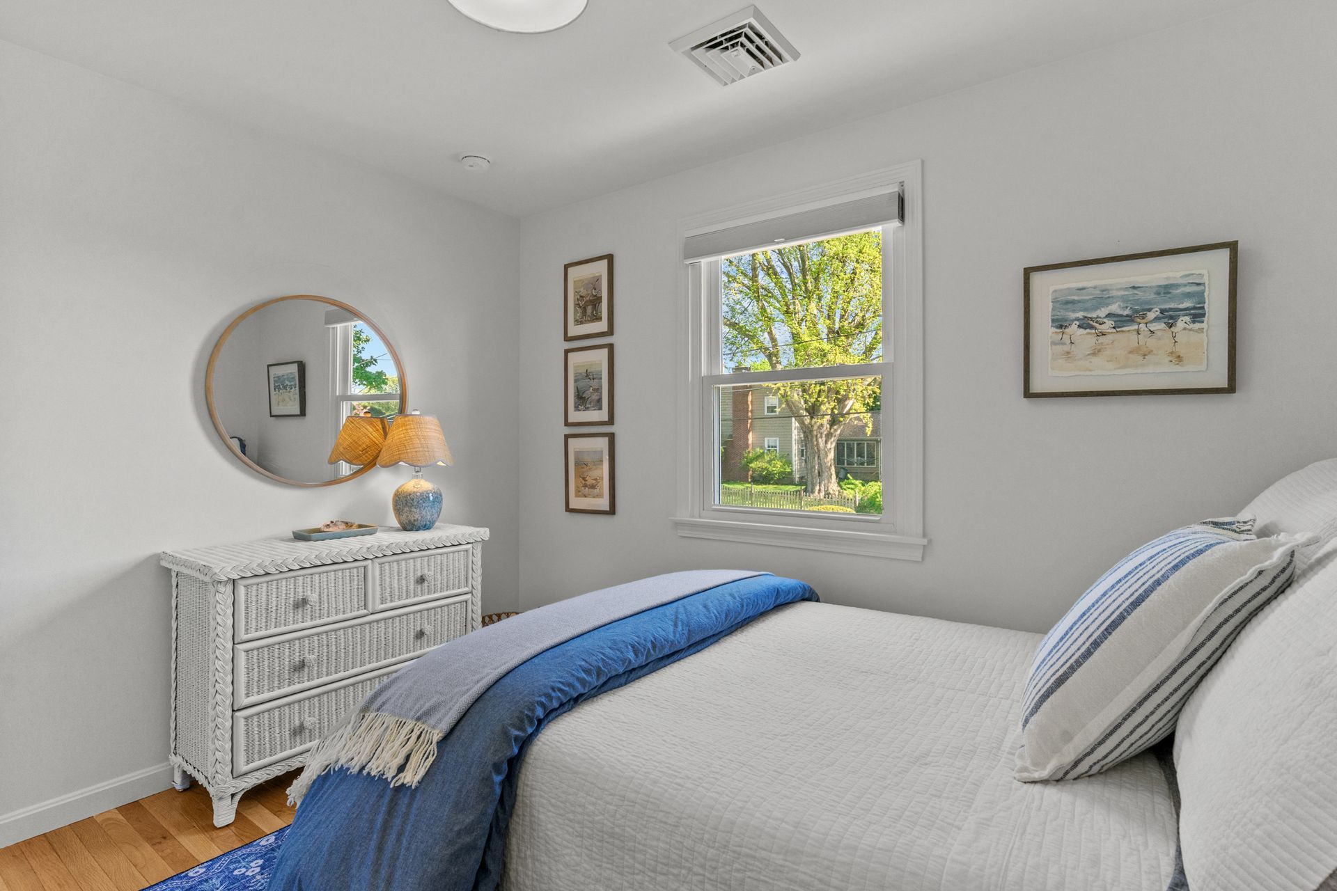 A bedroom with a bed , dresser , mirror and window.
