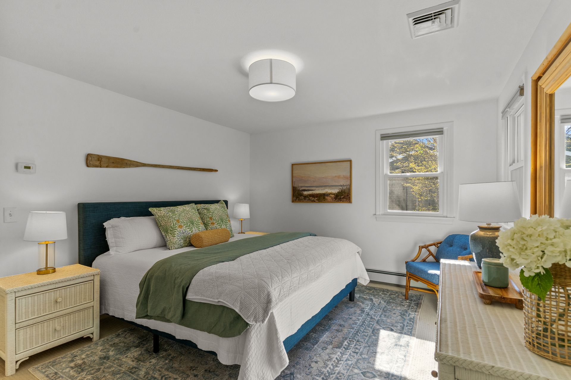 A bedroom with a bed , dresser , chair and mirror.