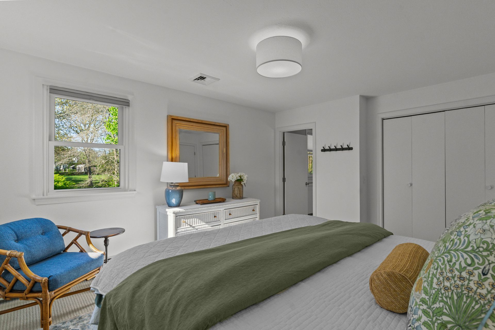 A bedroom with a large bed , dresser , chair and window.
