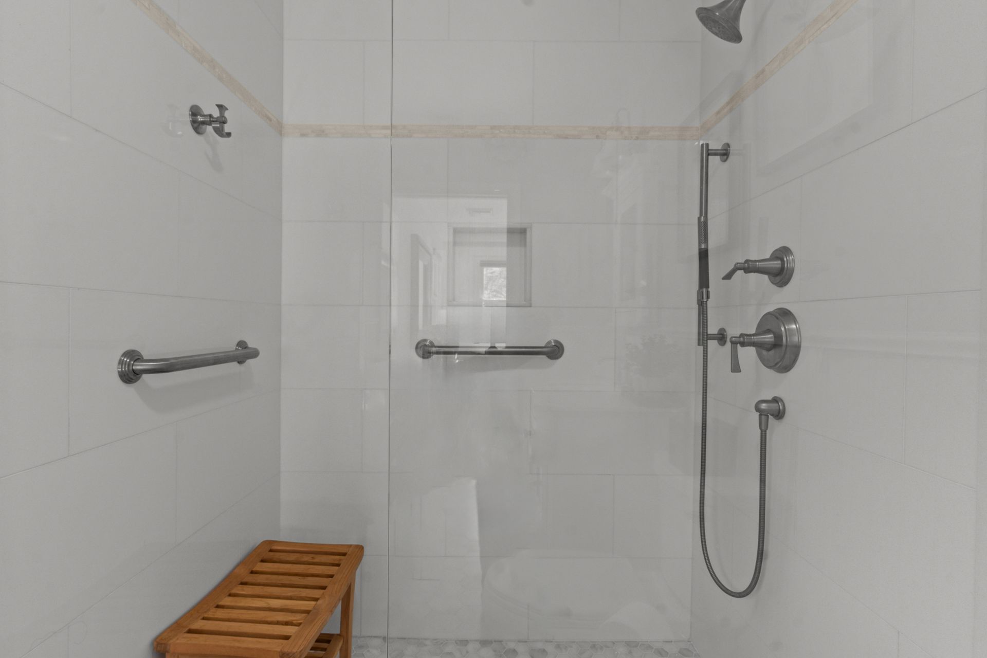 A bathroom with a walk in shower and a bench.