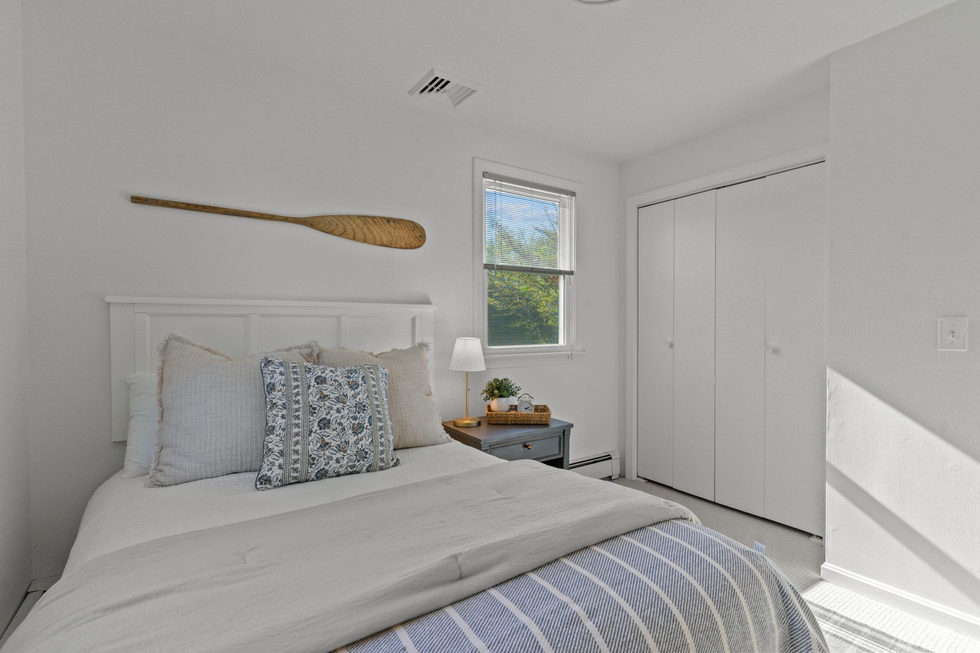 A bedroom with a bed , nightstand , window and closet.
