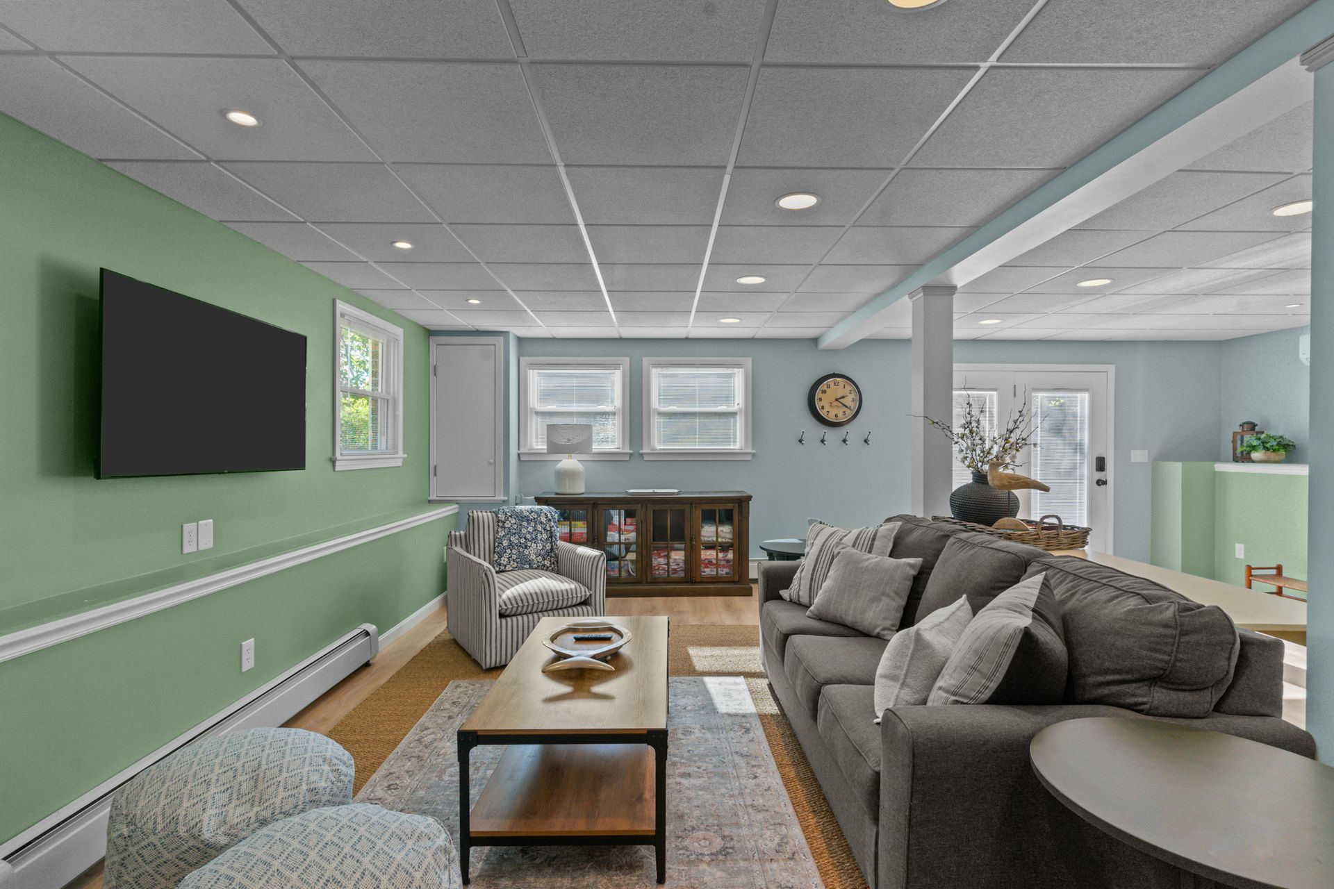 A living room with a couch , chairs , a coffee table and a flat screen tv.