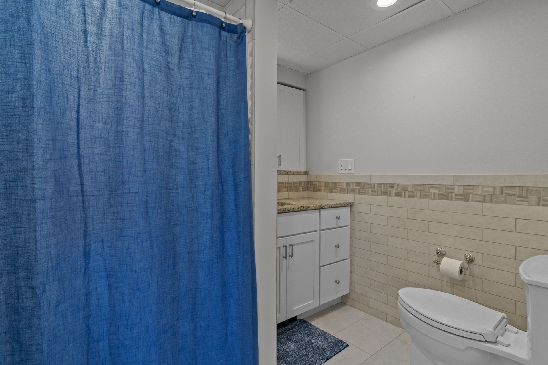 A bathroom with a blue shower curtain and a toilet.