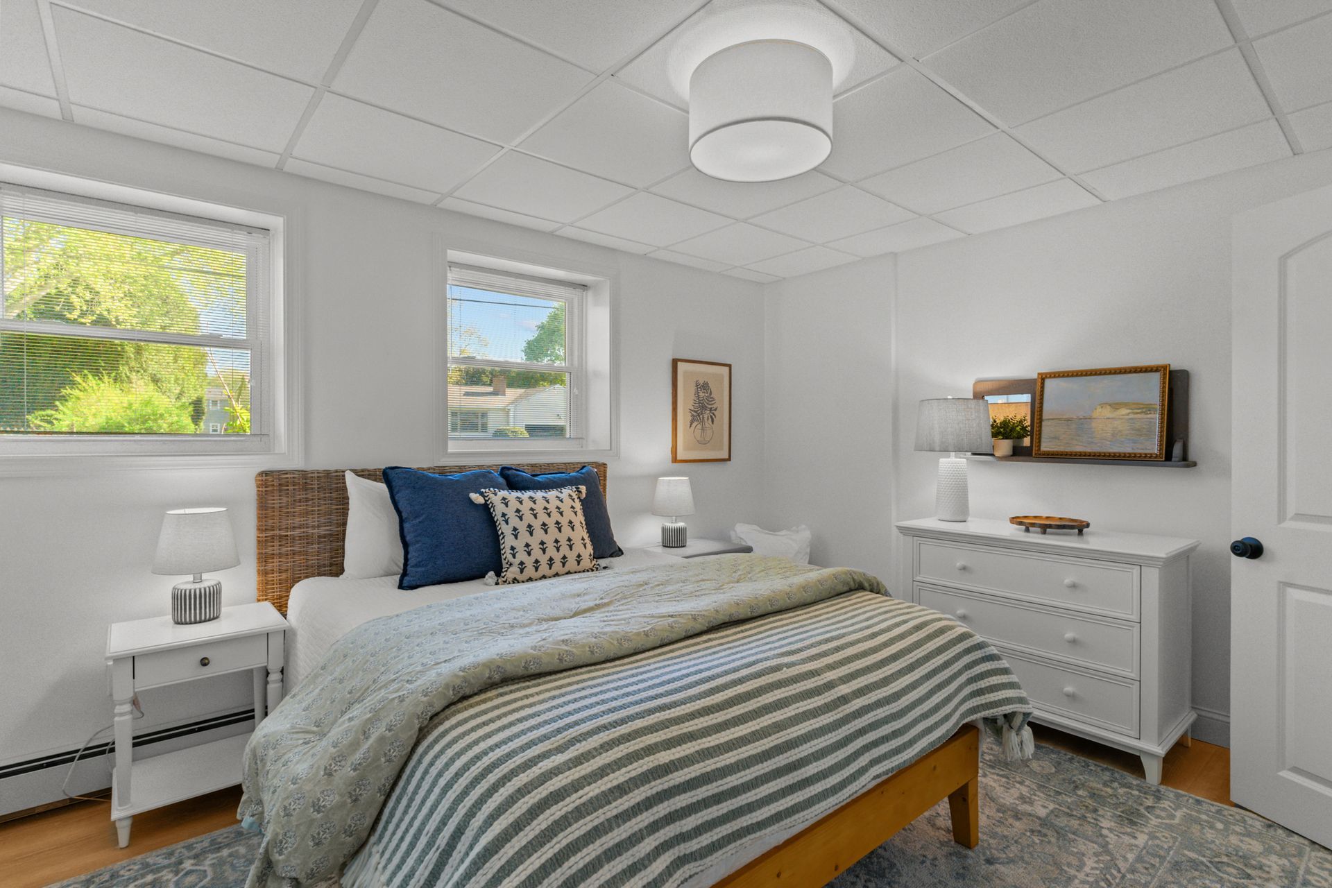 A bedroom with a bed , dresser , nightstand and window.