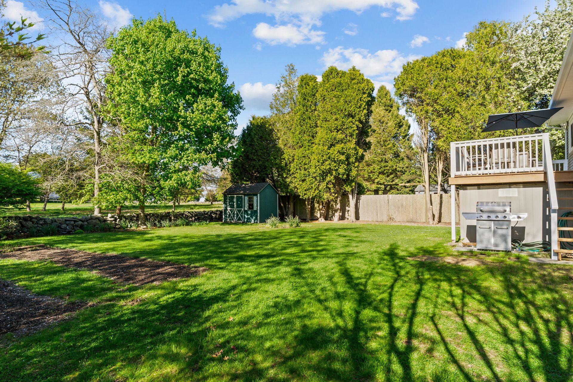 A large lush green yard with trees and a house in the background.