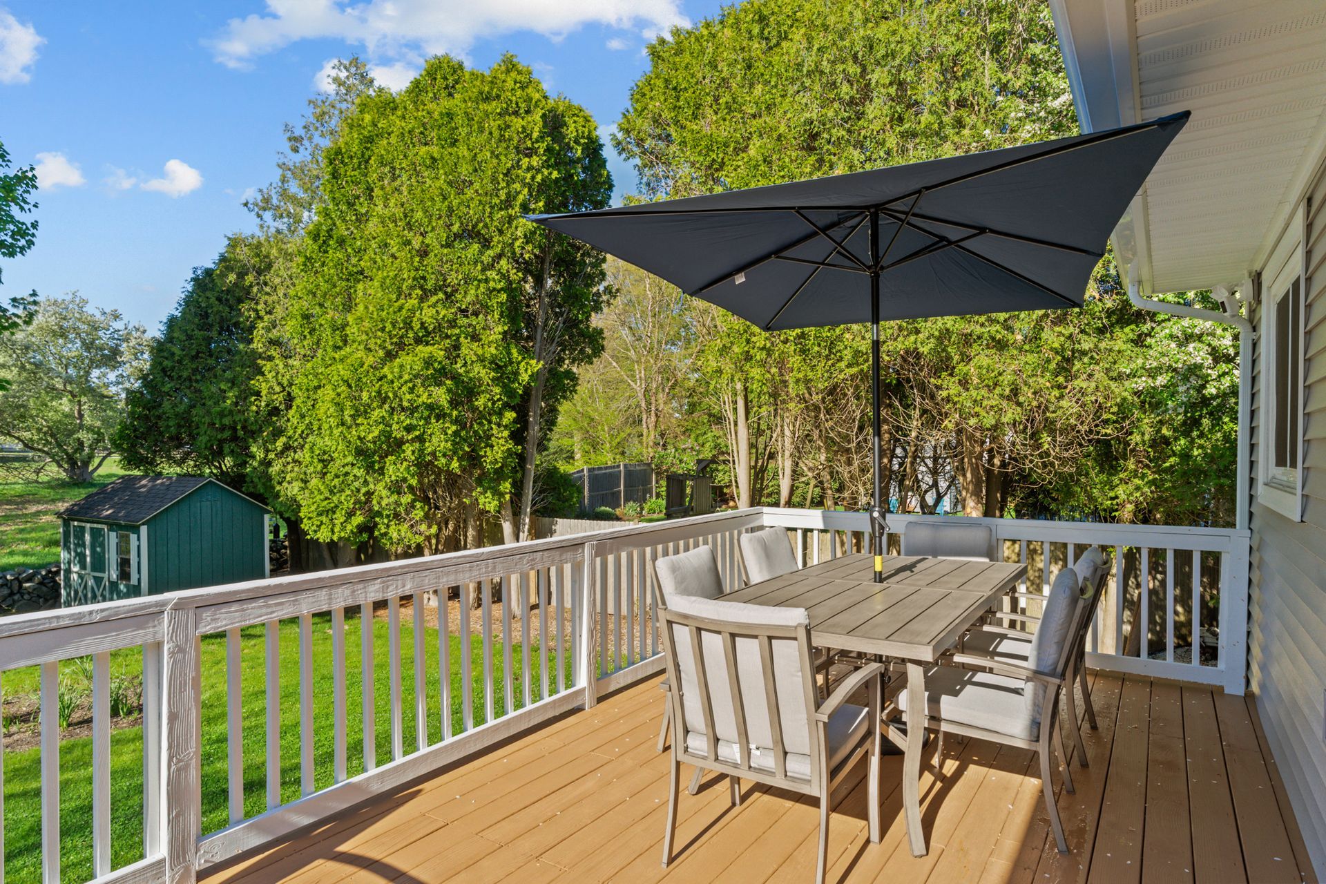 A deck with a table and chairs and an umbrella.