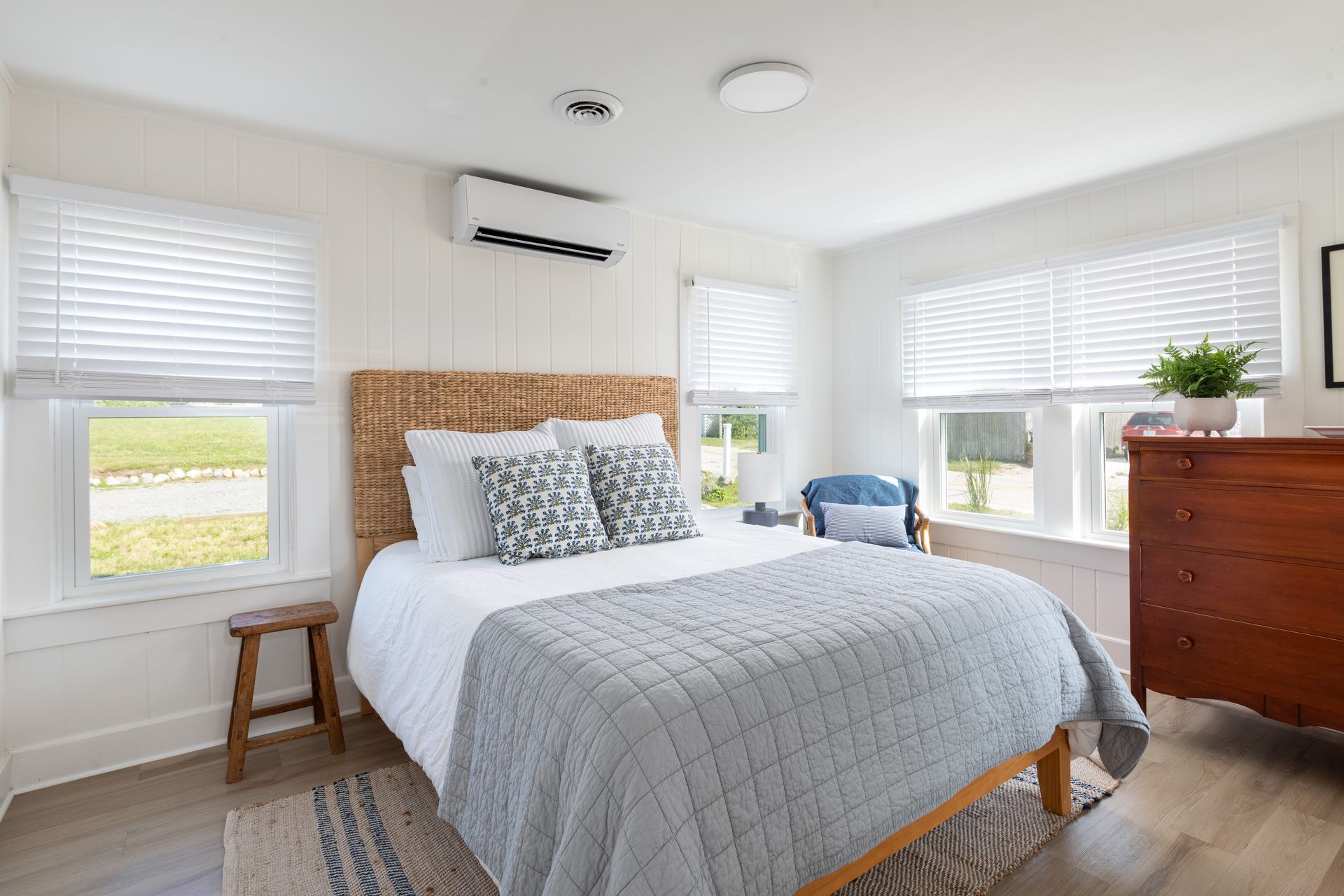 A bedroom with a bed , dresser , chair and window.