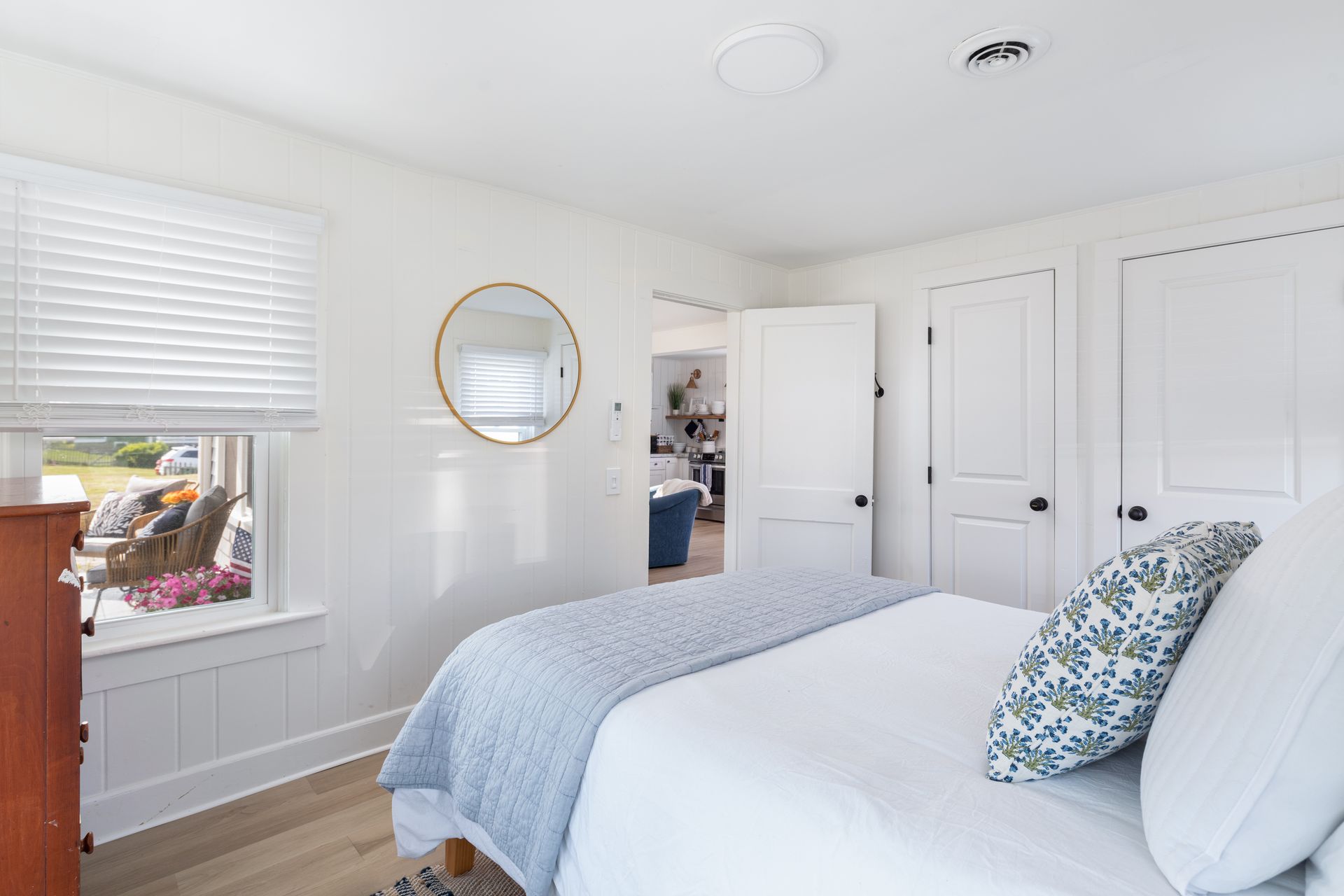 A bedroom with a bed , dresser , mirror and window.