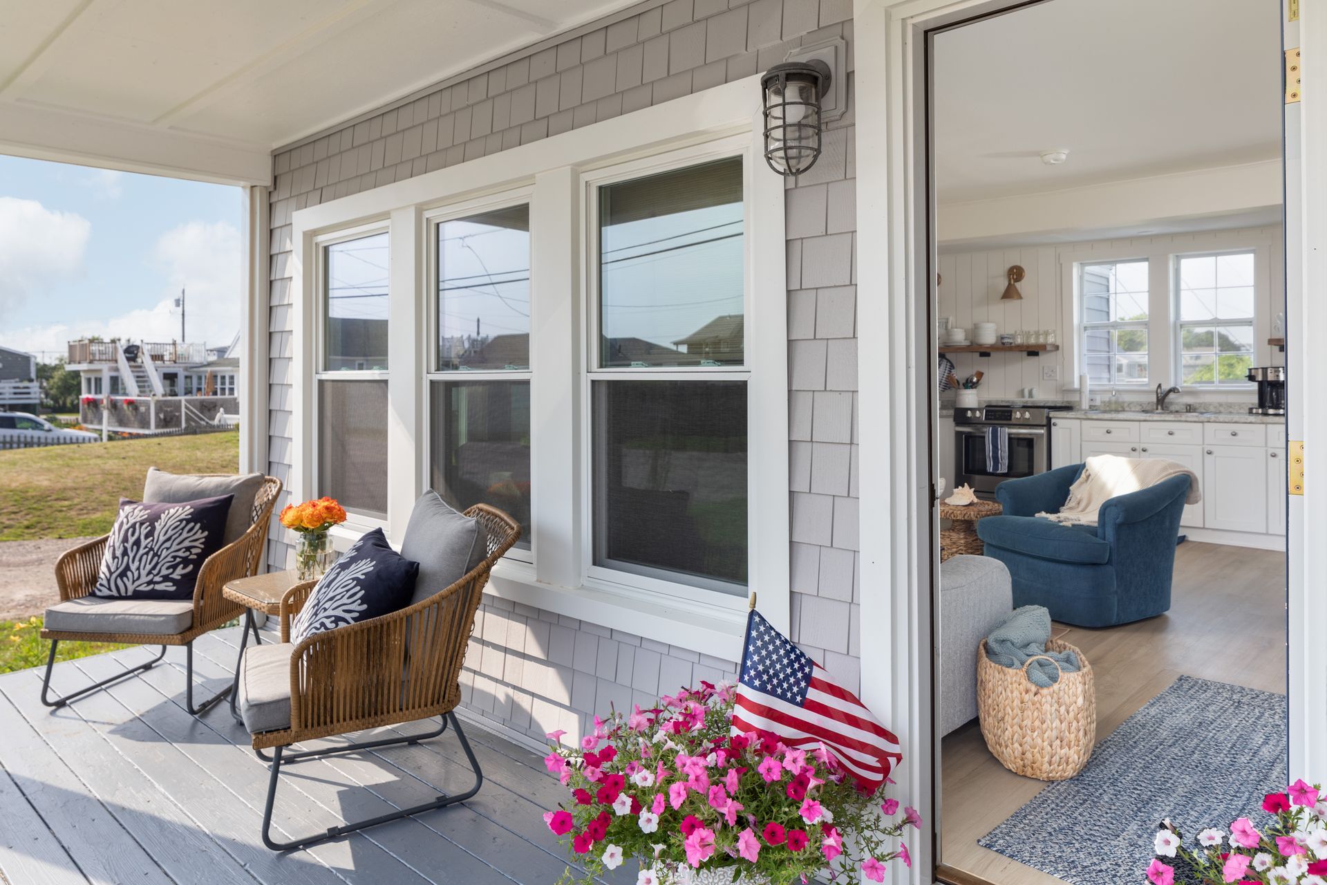There is a porch with chairs and an american flag on it.