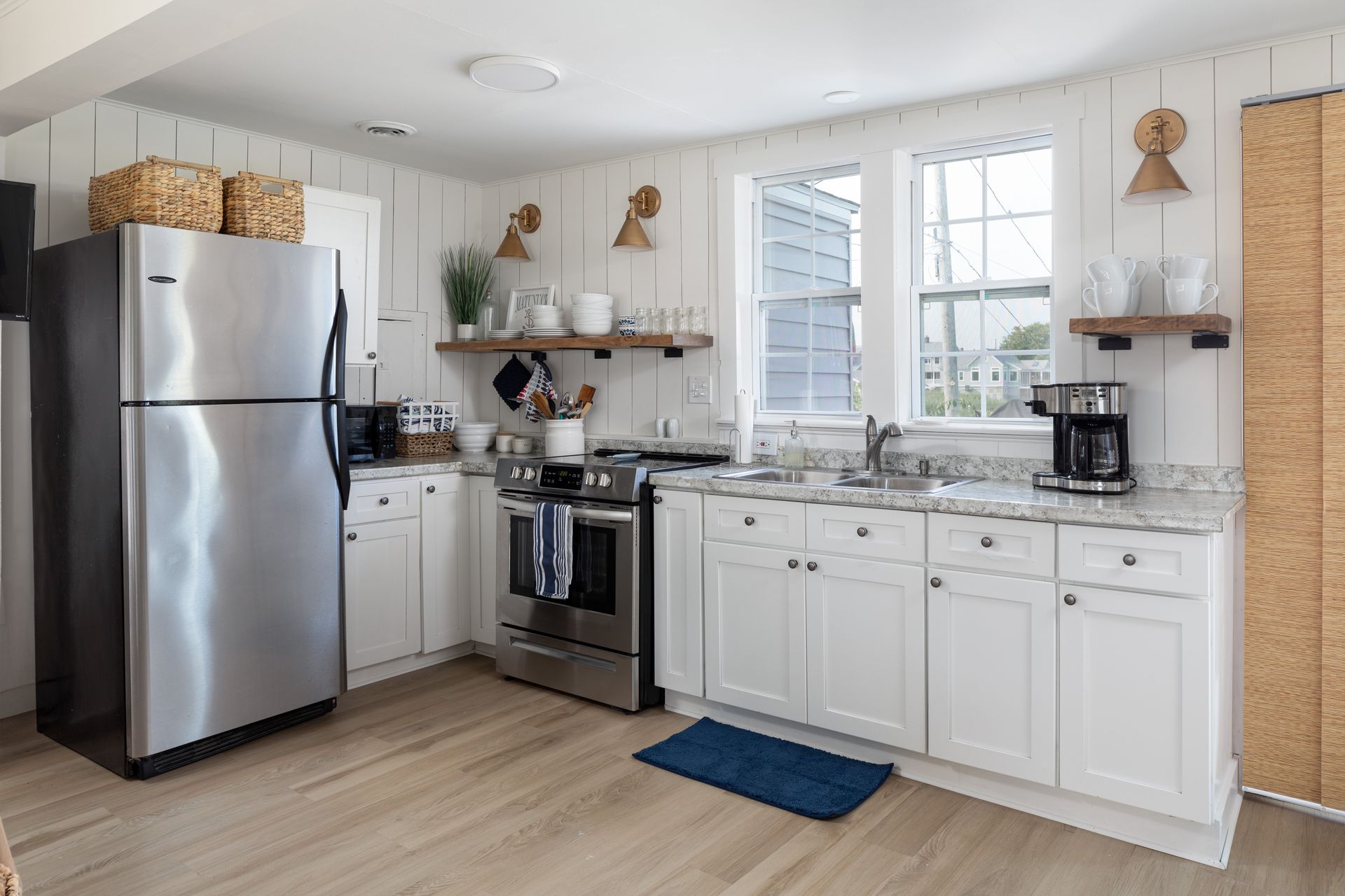 A kitchen with white cabinets , stainless steel appliances , a refrigerator , stove , and sink.