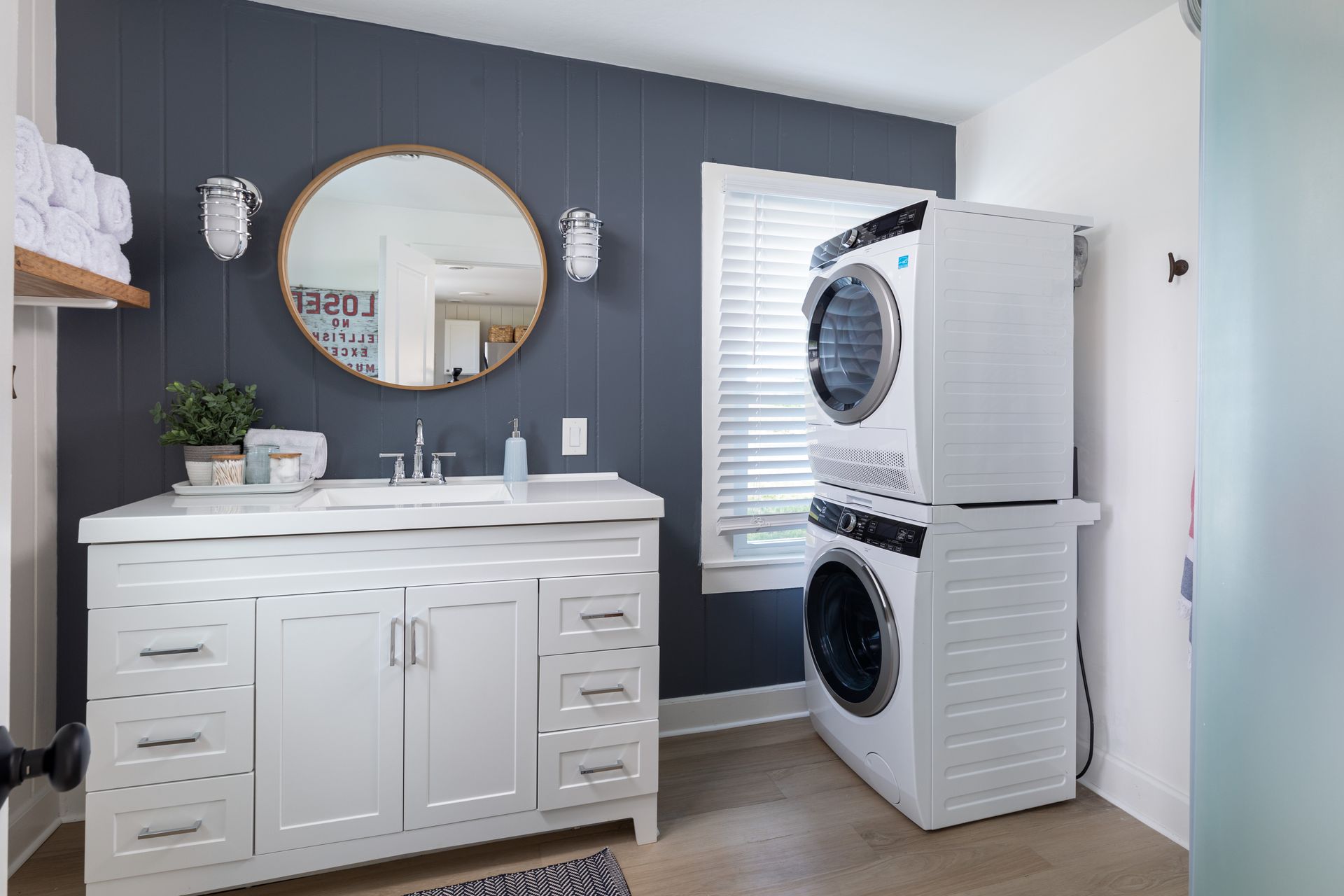 A bathroom with a sink , washer and dryer stacked on top of each other.