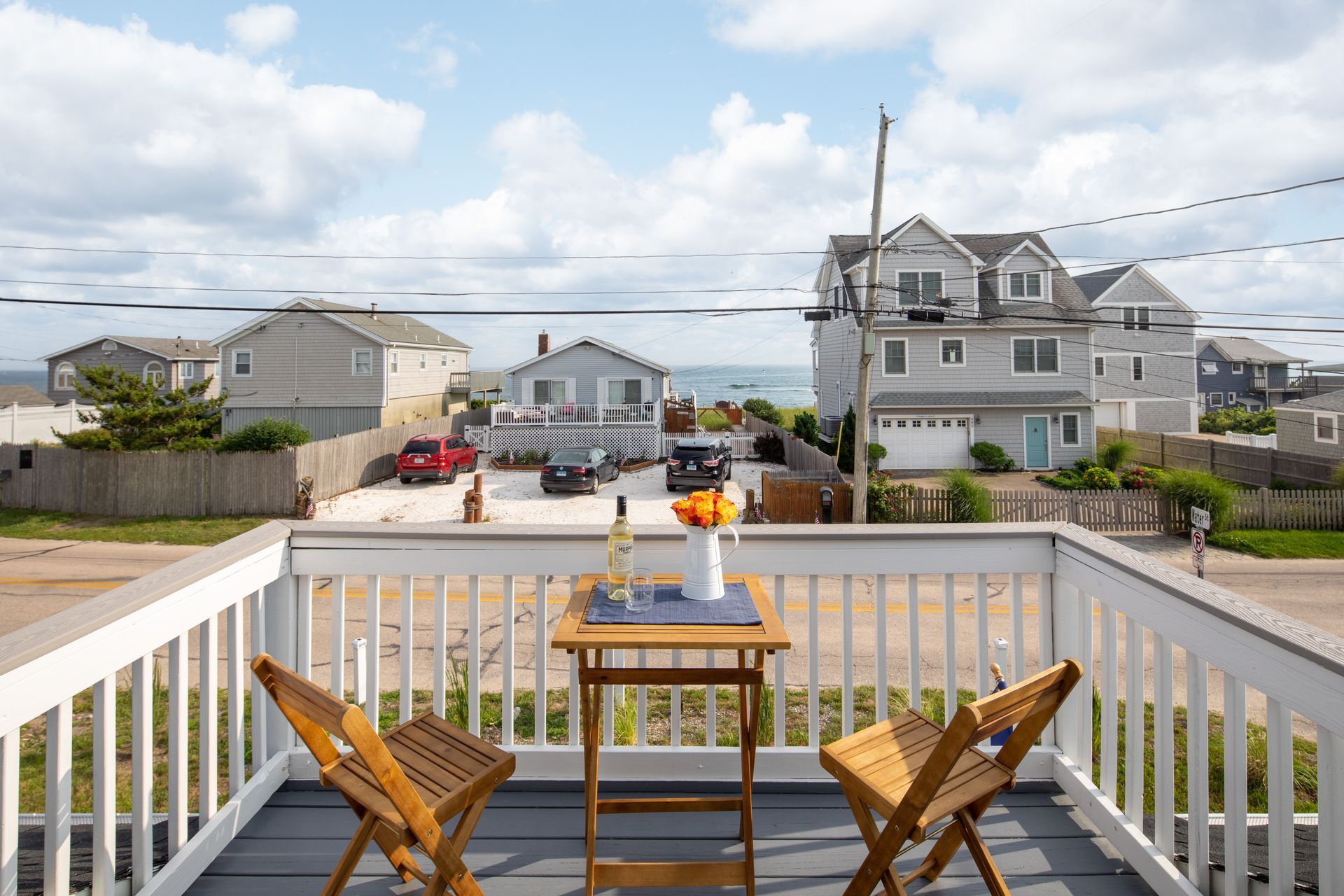 A balcony with a table and chairs overlooking the ocean.