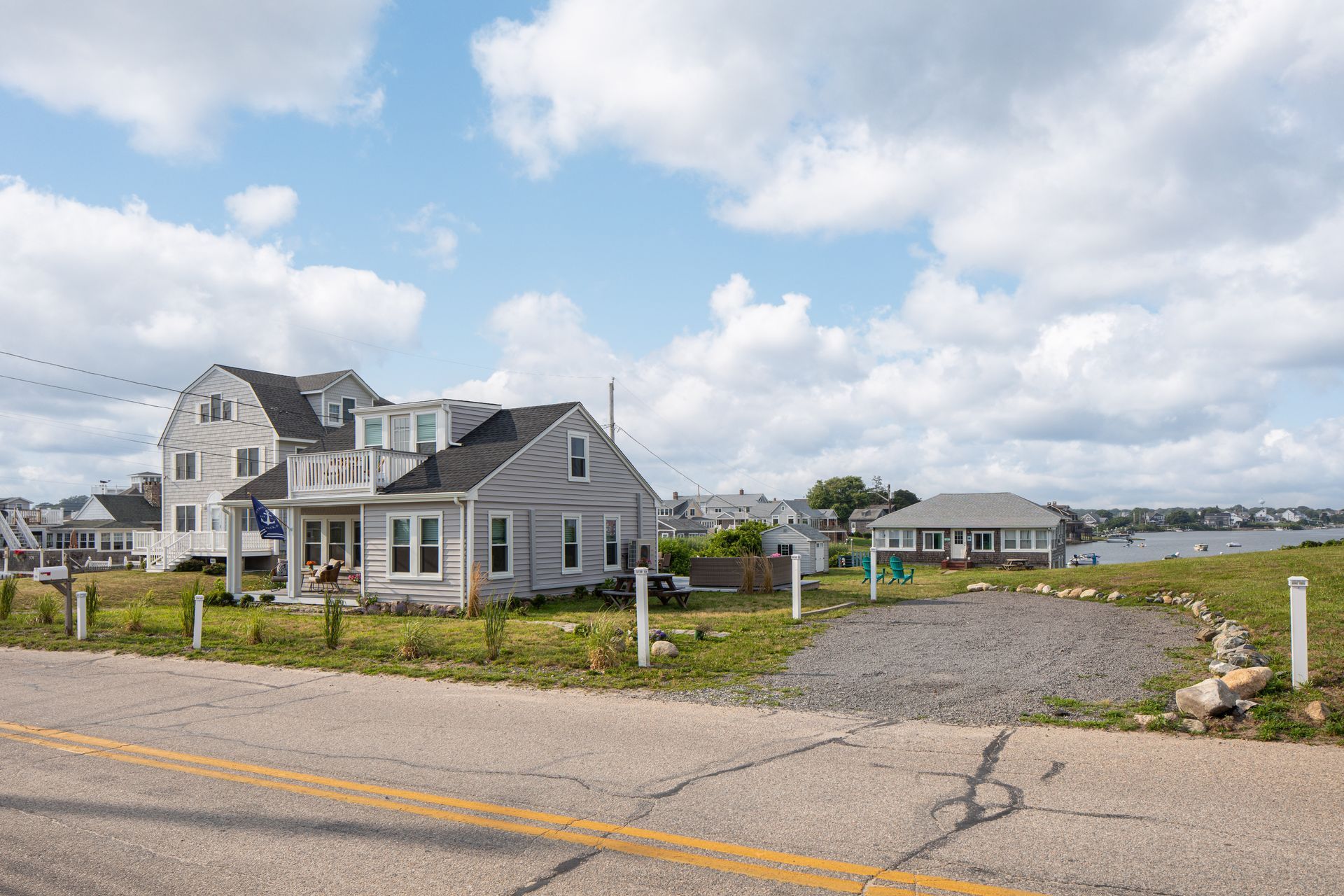 A house is sitting on the side of a road next to a body of water.