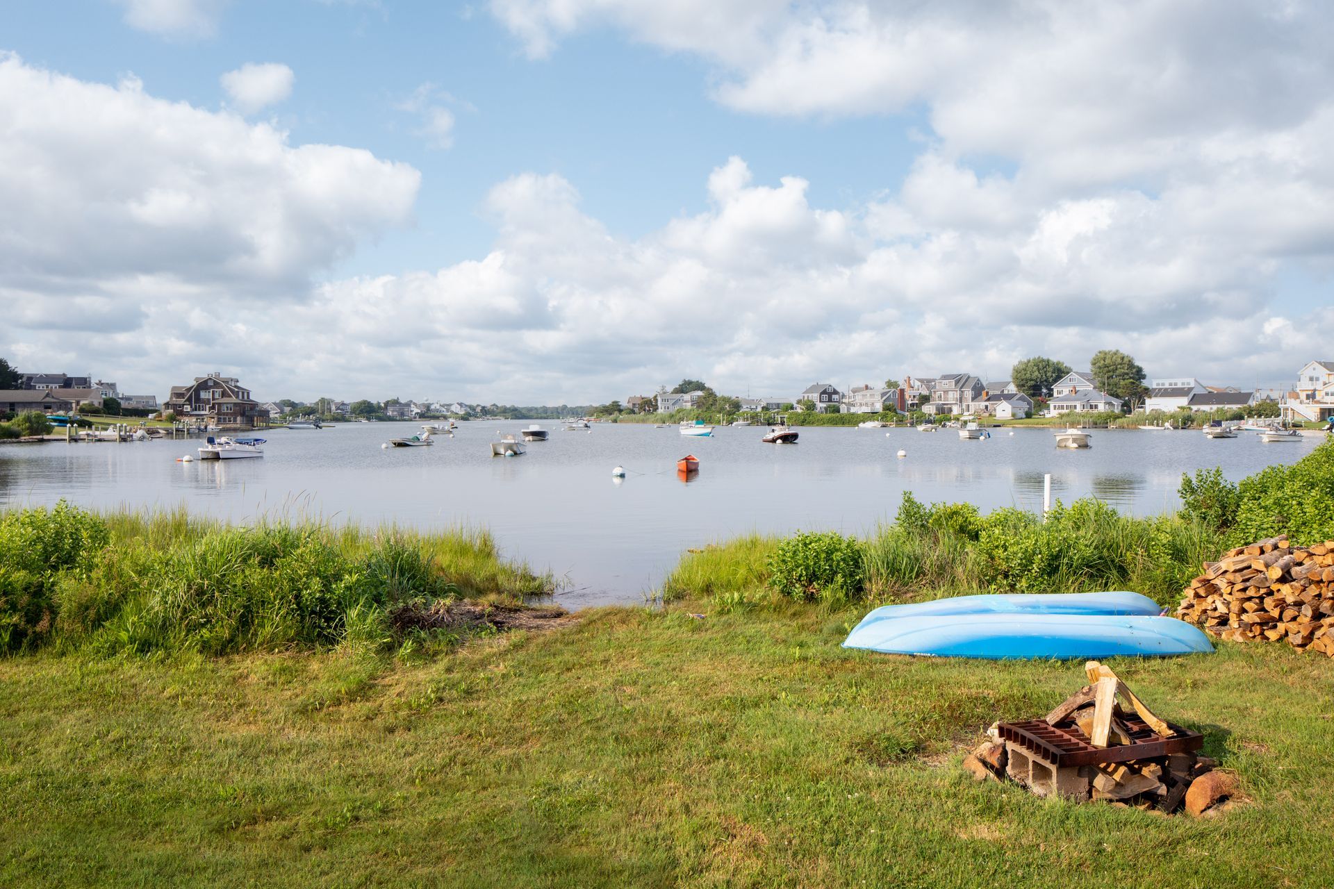 A blue kayak is sitting next to a fire pit on the shore of a lake.