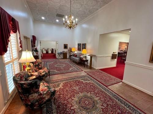 Elegant reception room with patterned rugs, floral chairs, and a chandelier.