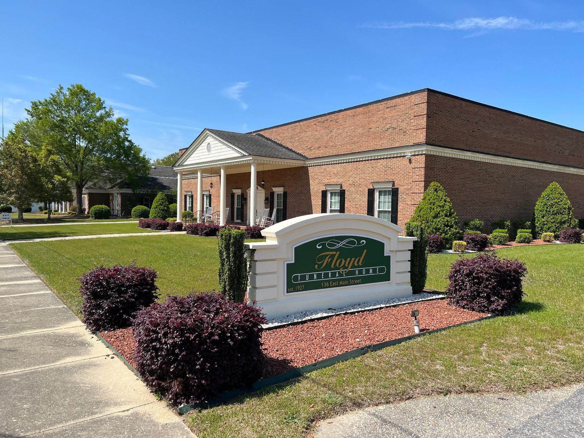 Funeral home building with a sign and landscaping under a blue sky.