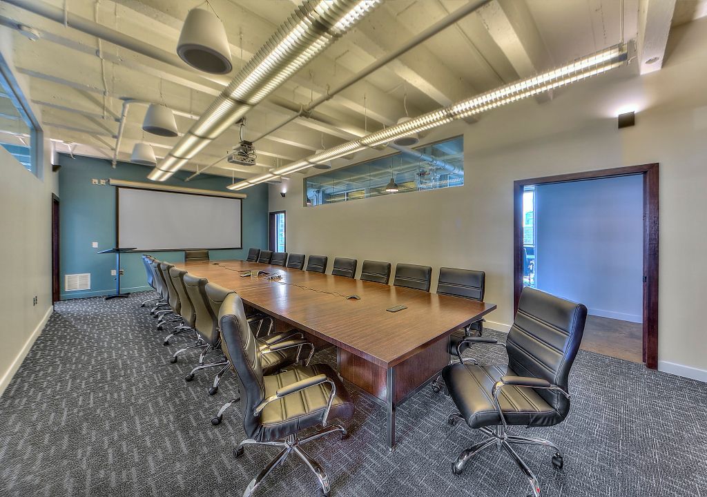 A conference room with a long table and chairs and a projector screen.
