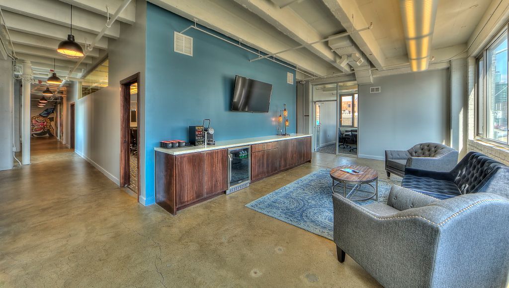 A living room with a couch , chairs , and a television on the wall.
