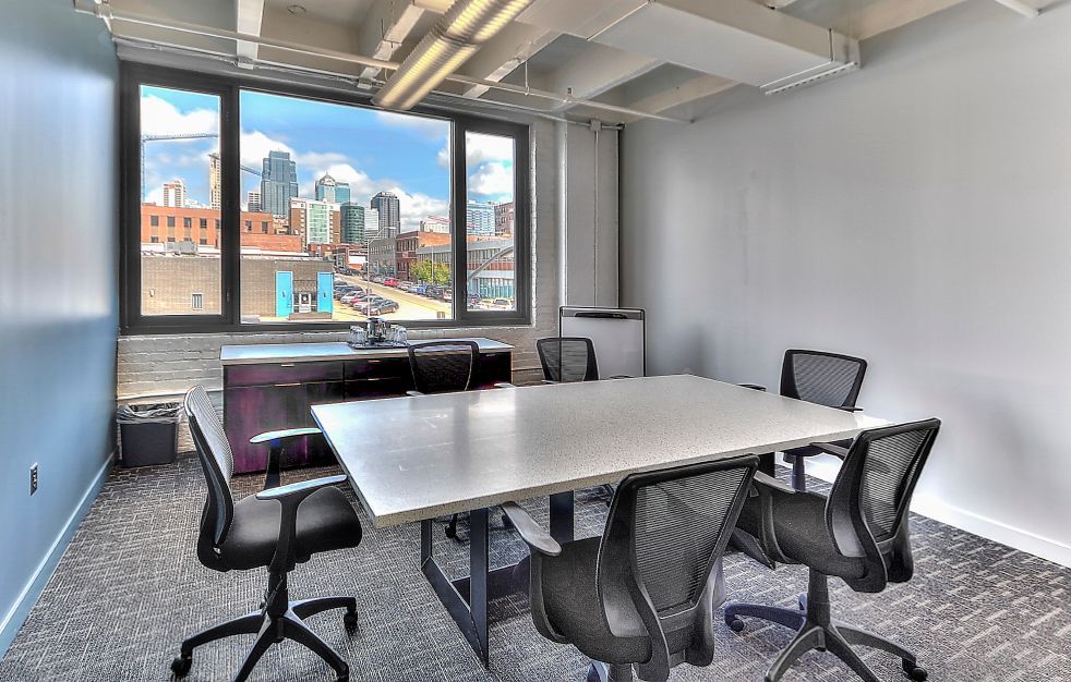 A conference room with a long table and chairs and a large window.