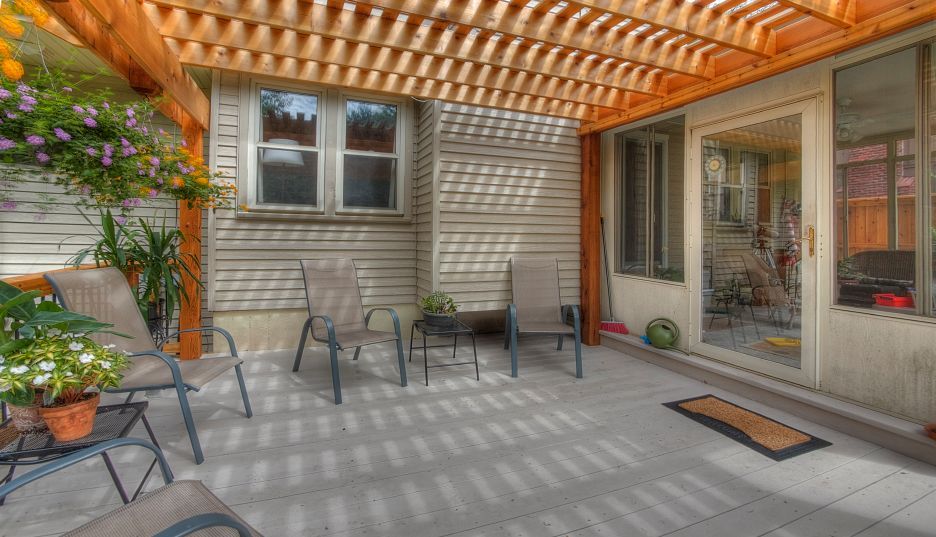 A patio with chairs and a table under a pergola.