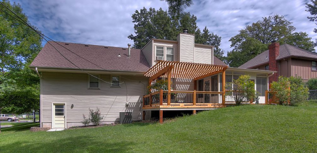 The back of a house with a large deck and a pergola.