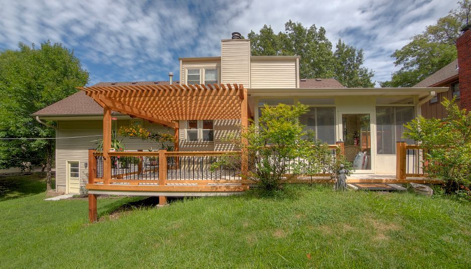 The back of a house with a wooden deck and a pergola.