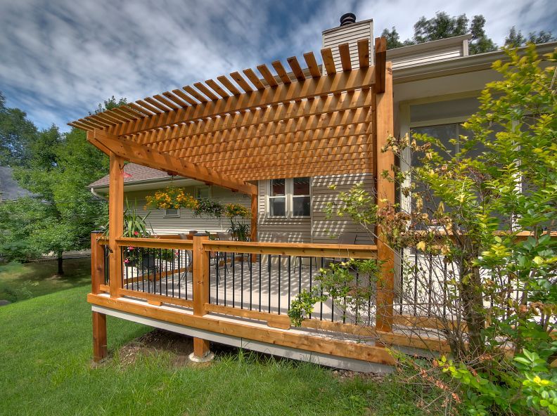 A wooden deck with a pergola on top of it.