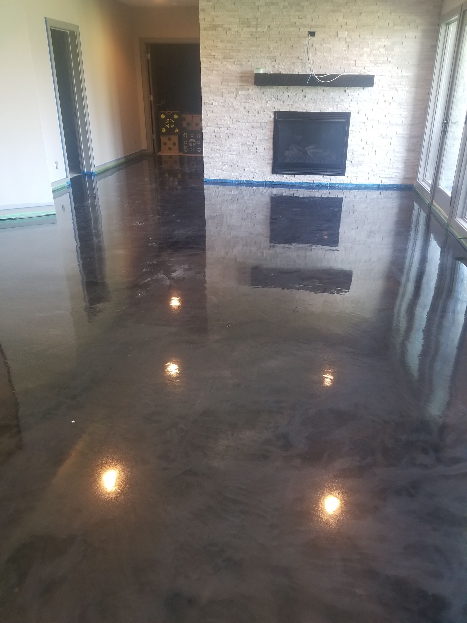 A living room with a shiny concrete floor and a fireplace.