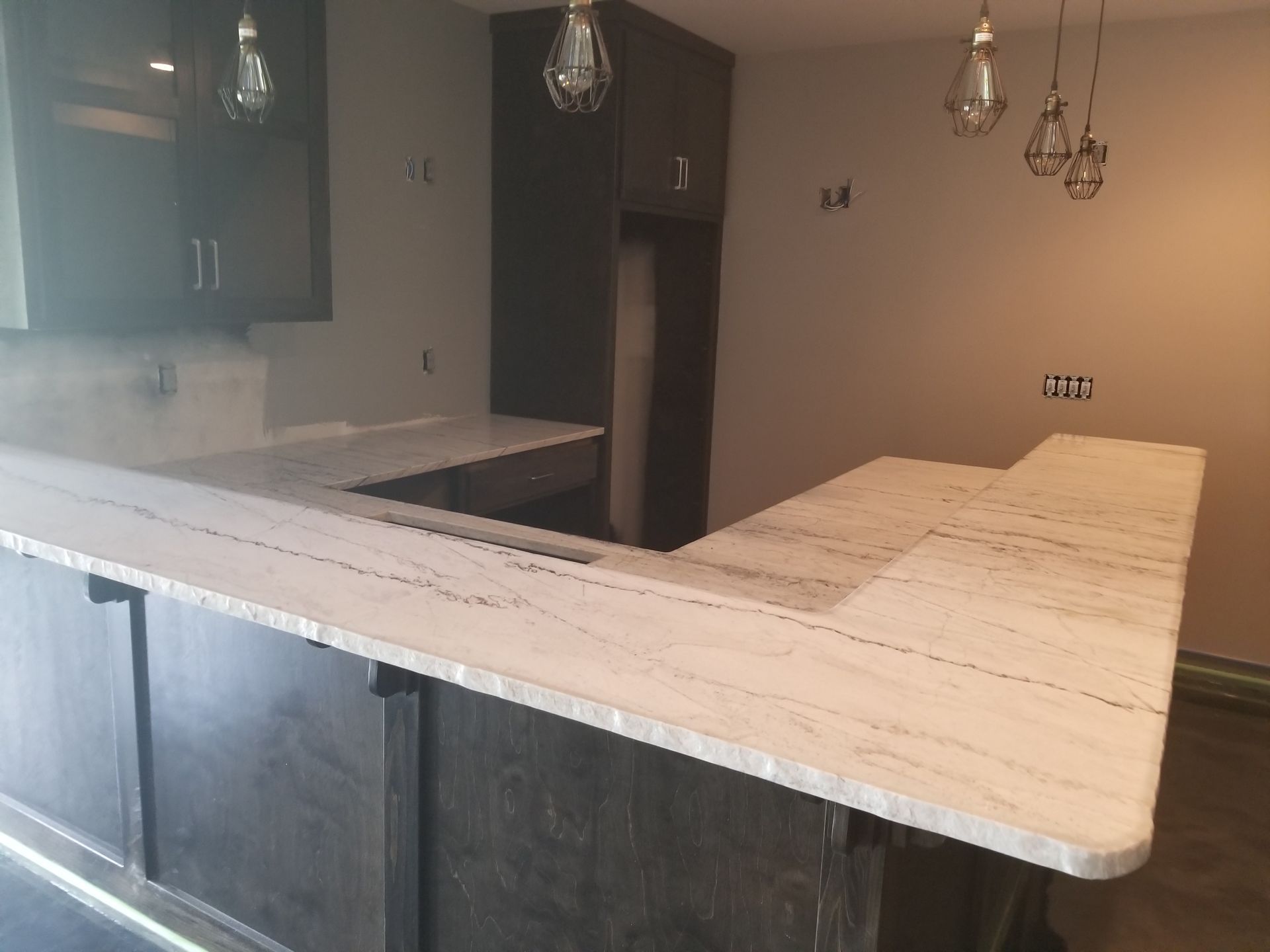 A kitchen with a marble counter top and black cabinets