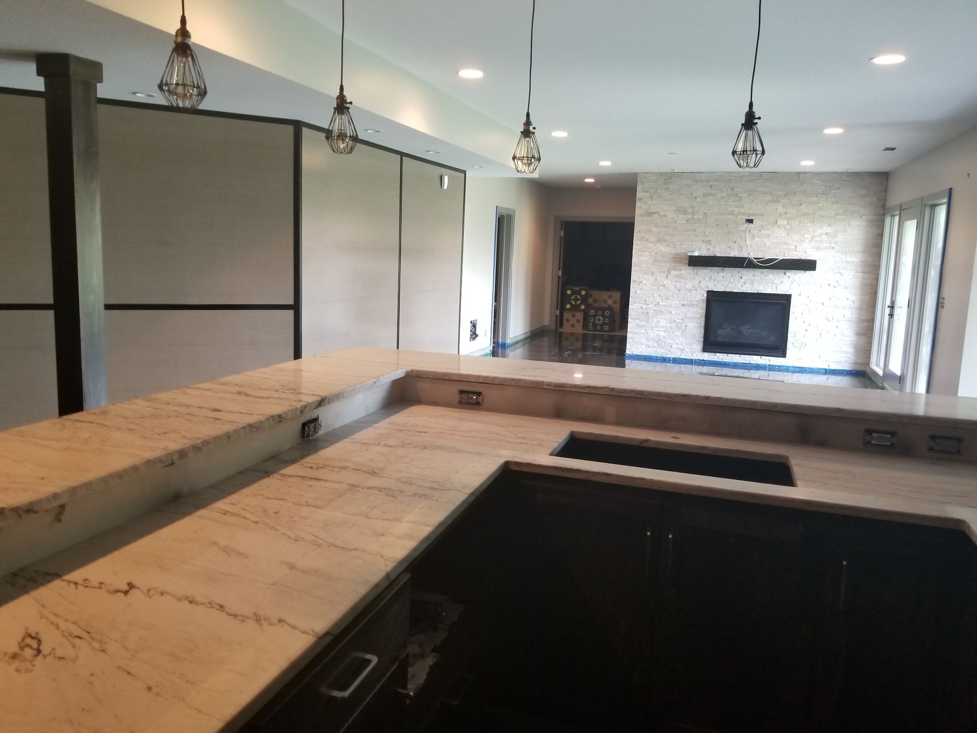 A kitchen with a sink and a fireplace in the background