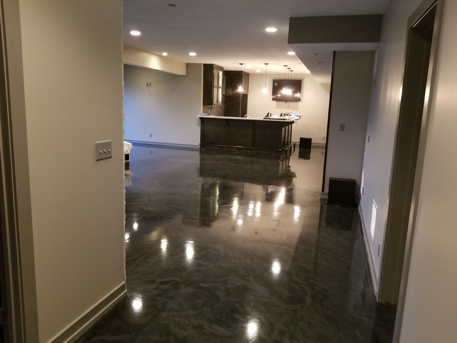 A hallway leading to a kitchen with a shiny concrete floor