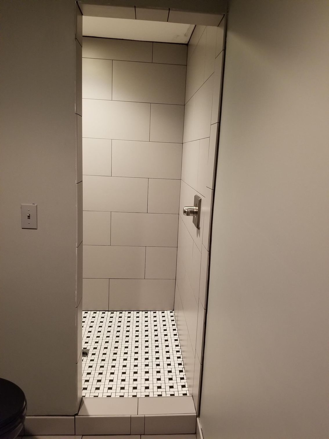 A bathroom with a walk in shower and a black and white tile floor.