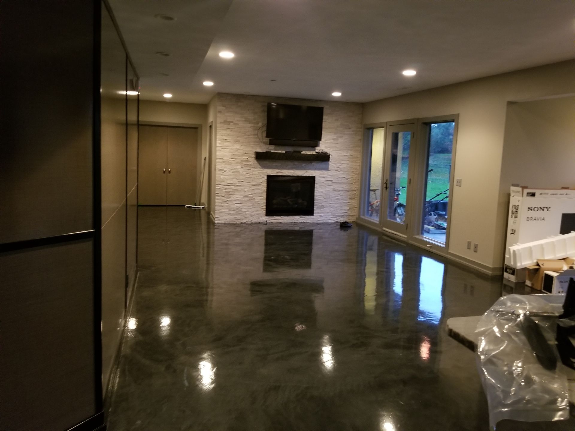A living room with a shiny concrete floor and a fireplace.