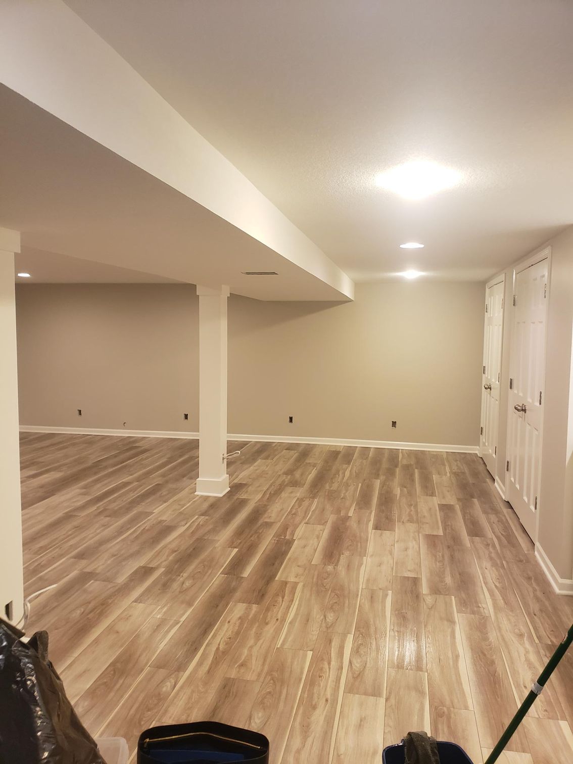 An empty basement with wooden floors and white walls.