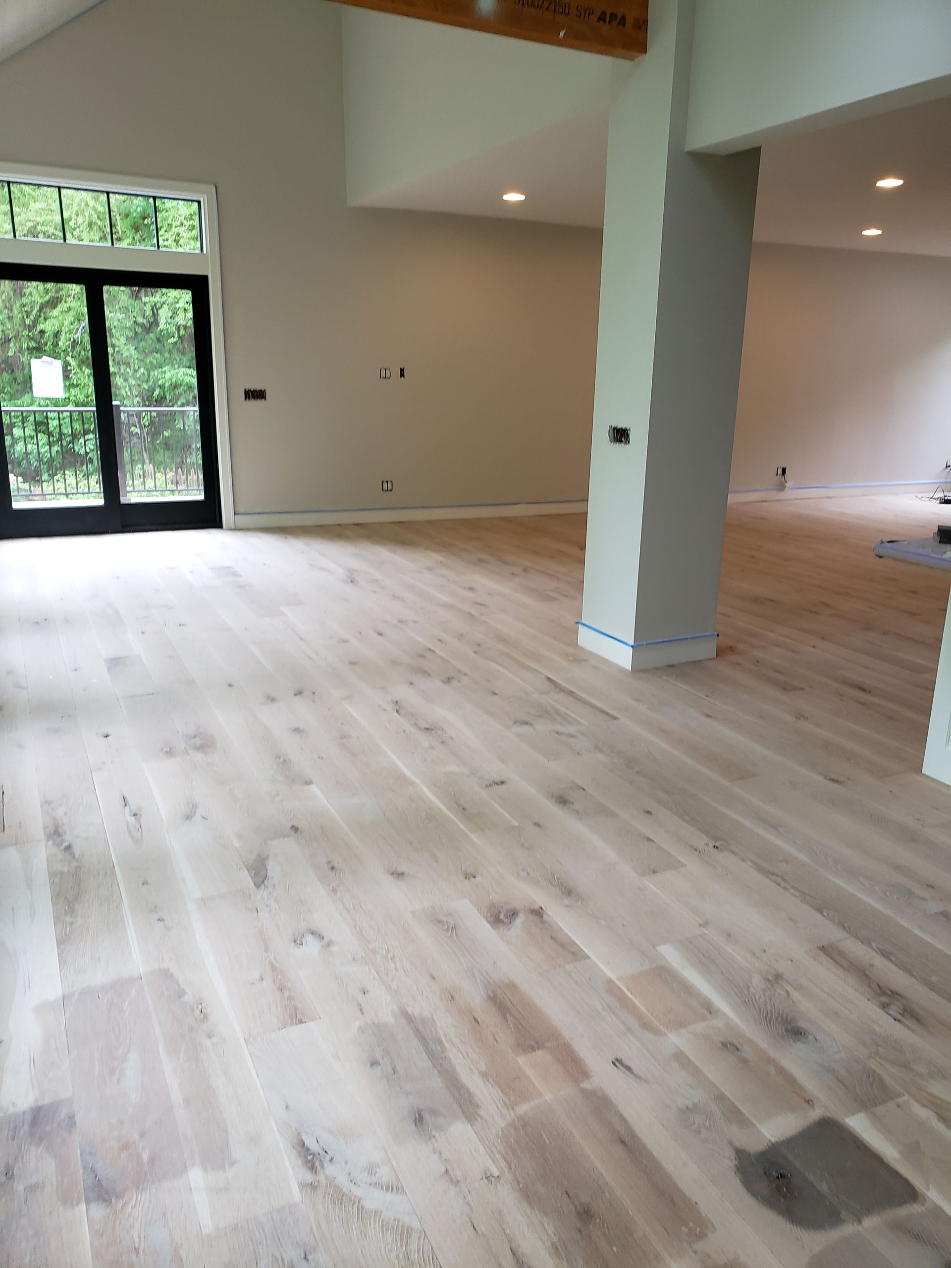 A large empty room with hardwood floors and a sliding glass door