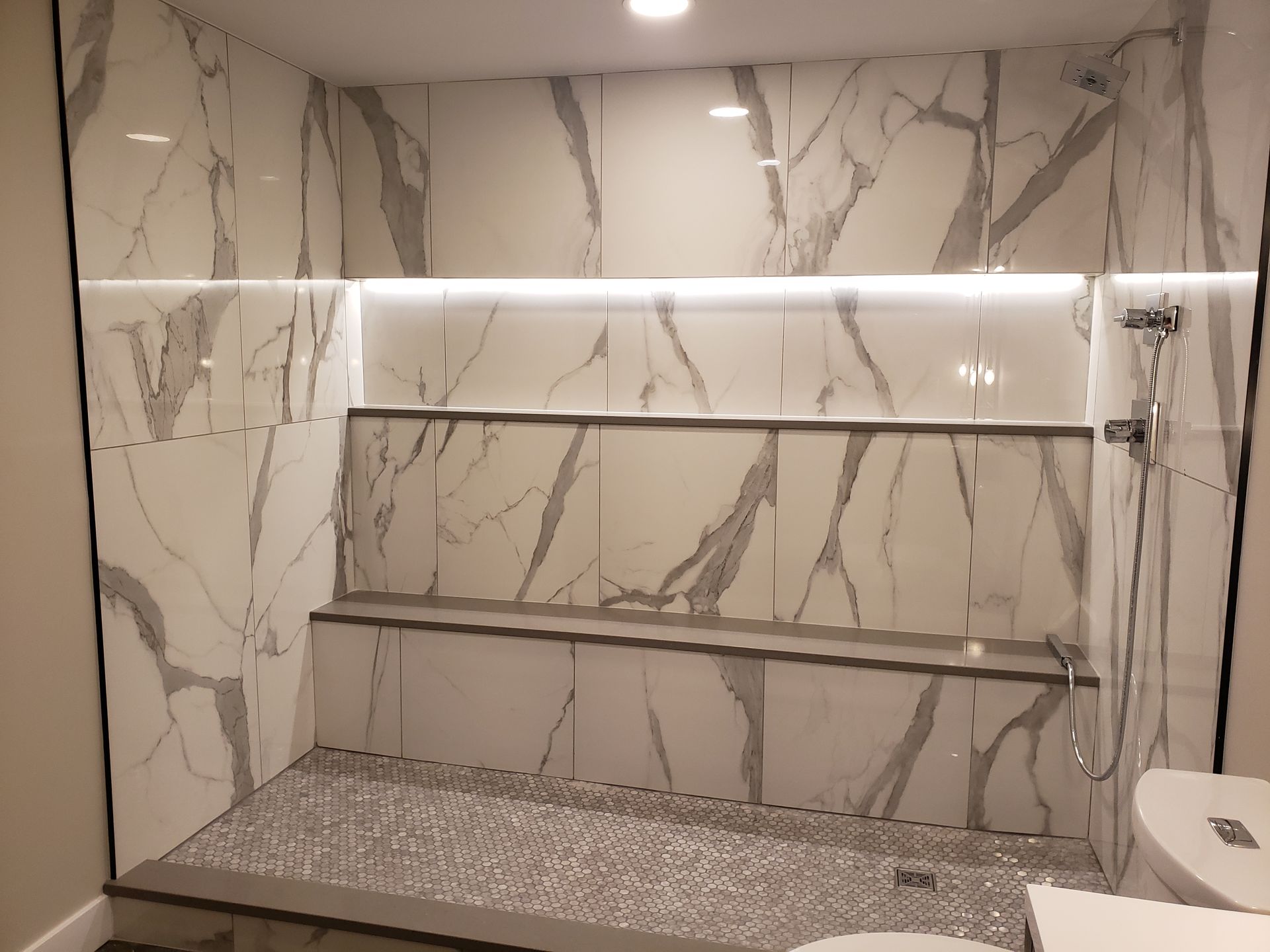 A bathroom with marble tiles and a walk in shower.