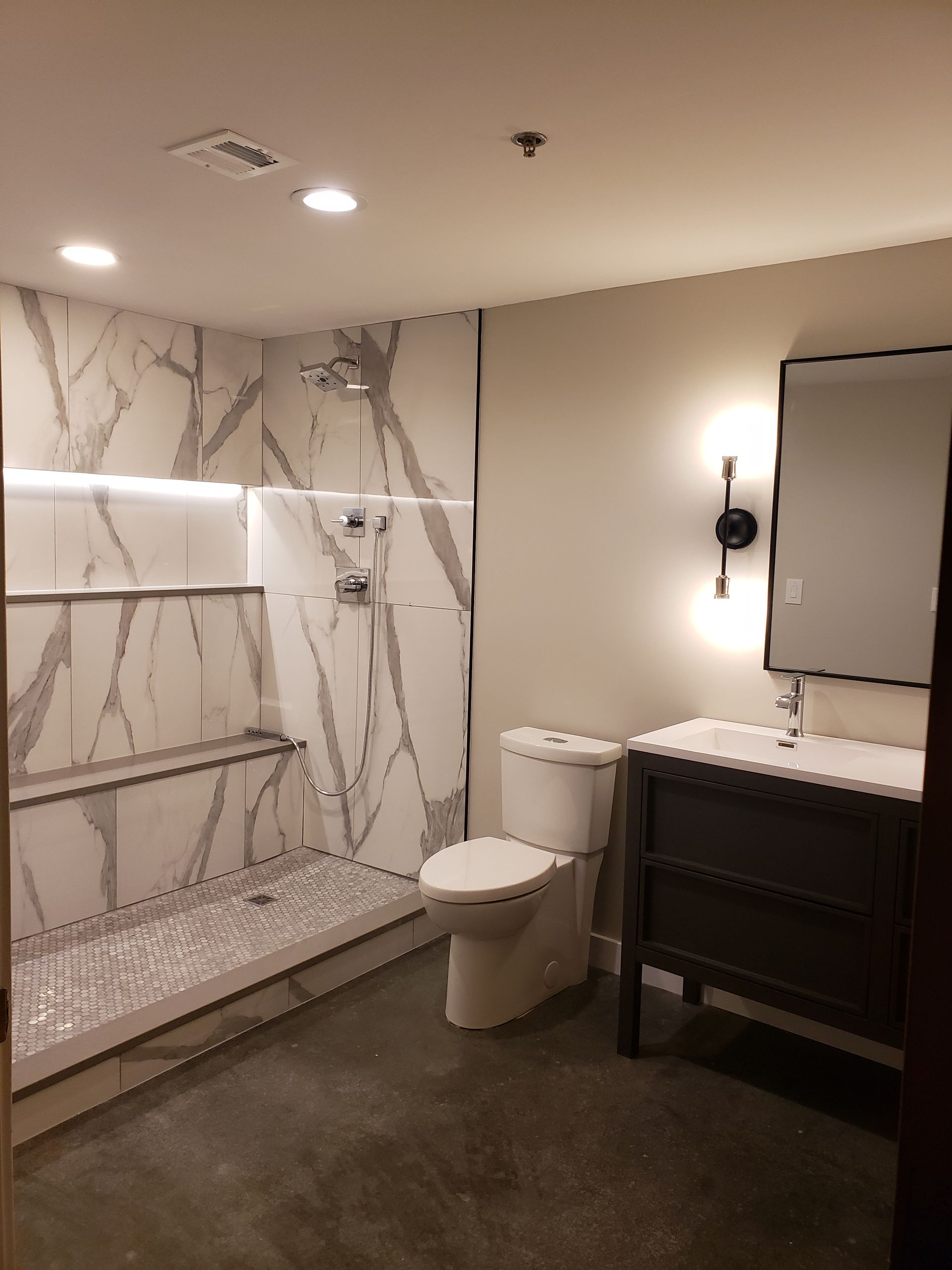 A bathroom with a toilet , sink , shower and mirror.