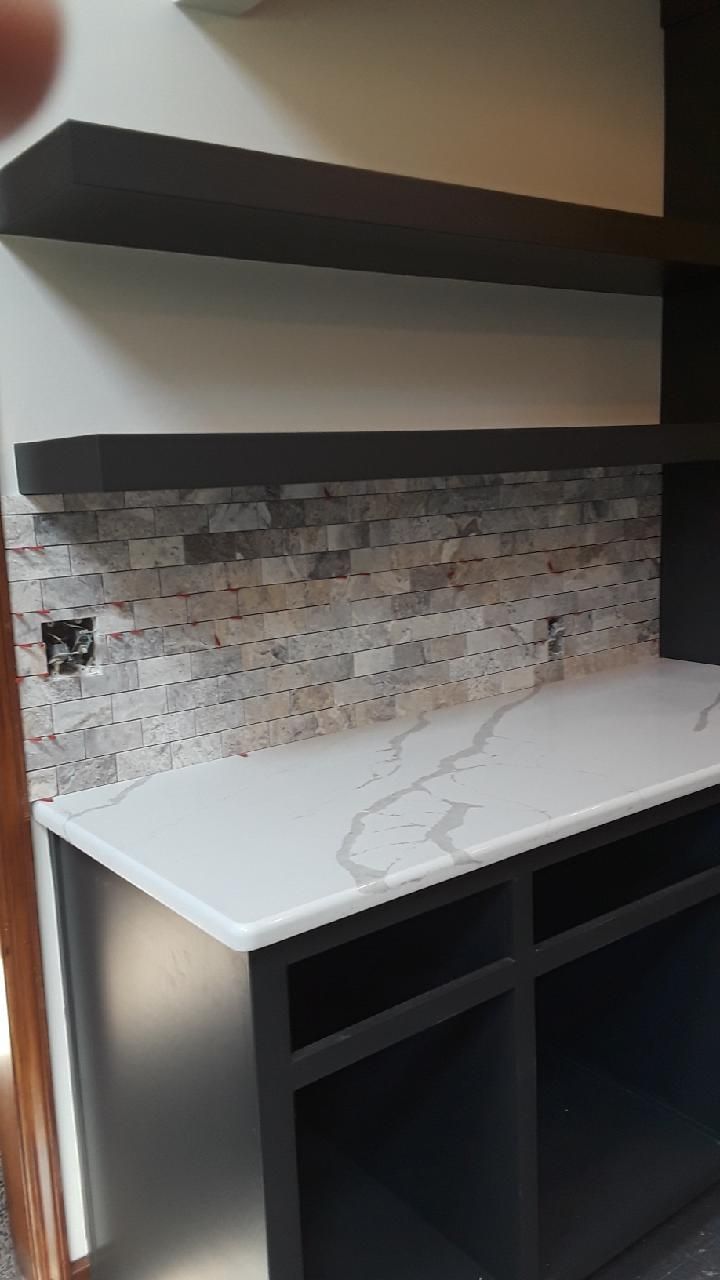 A kitchen with a marble counter top and stainless steel cabinets.