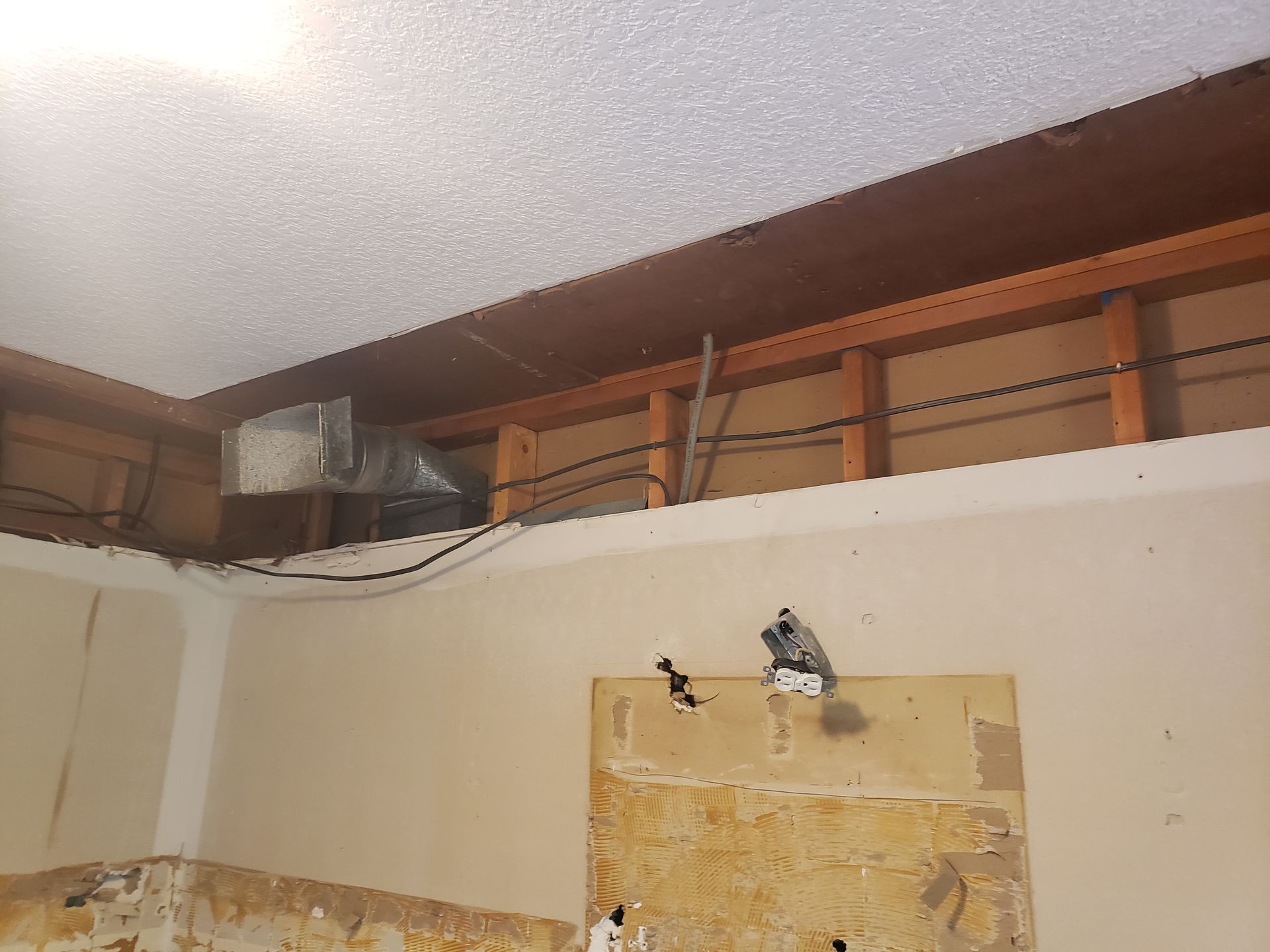 A room with a ceiling that is being remodeled with a lot of wires coming out of it.