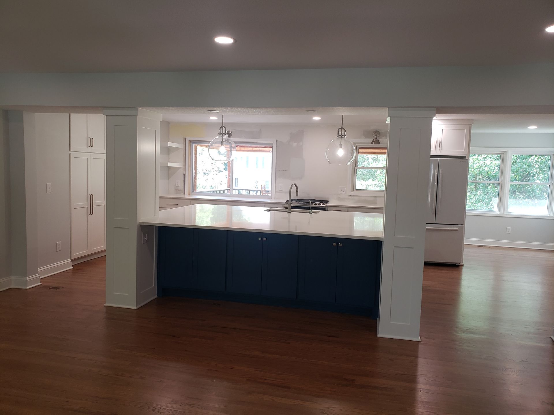 A kitchen with blue cabinets and white counter tops in a house.