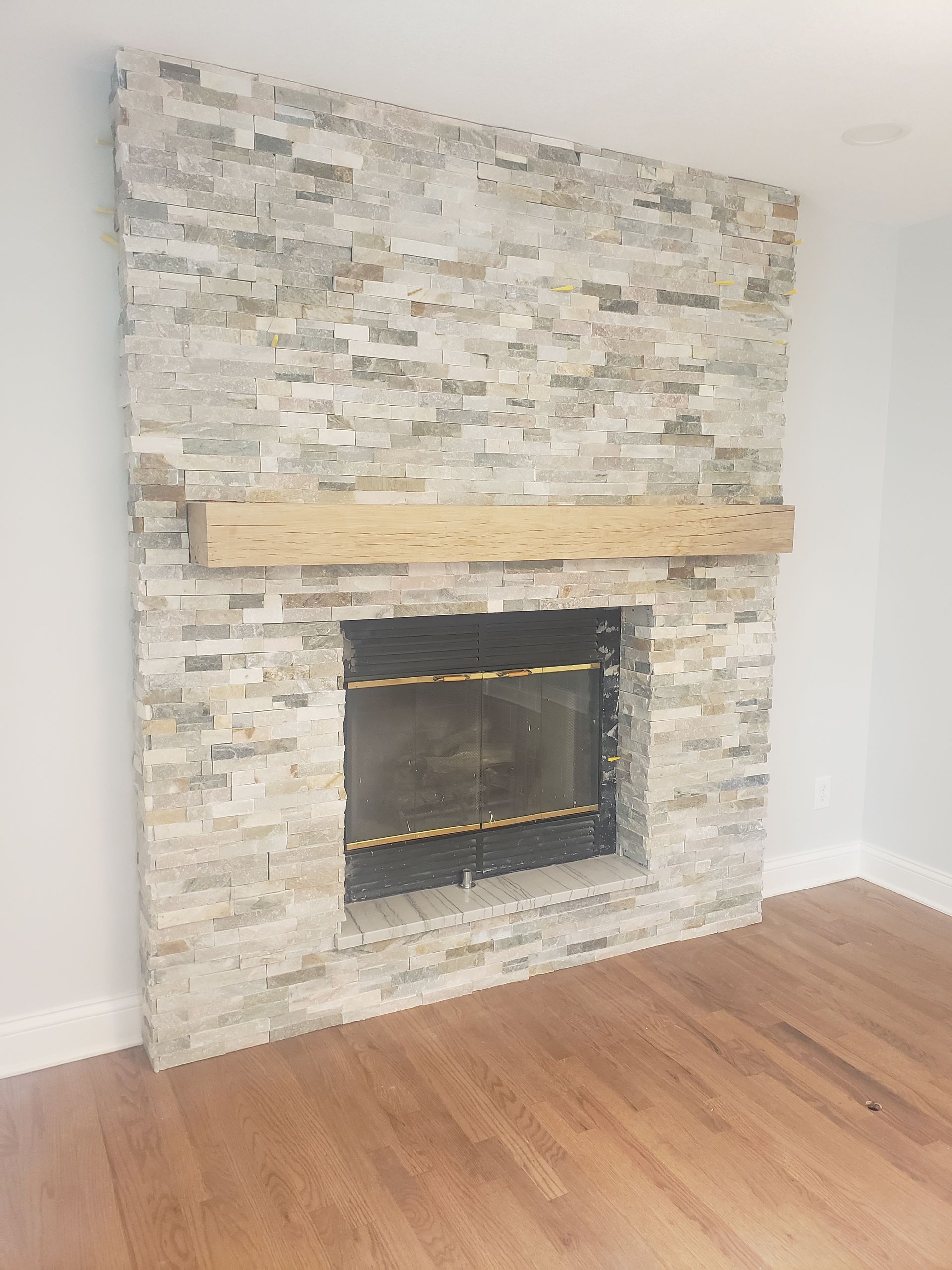 A fireplace in a living room with a wooden mantle.
