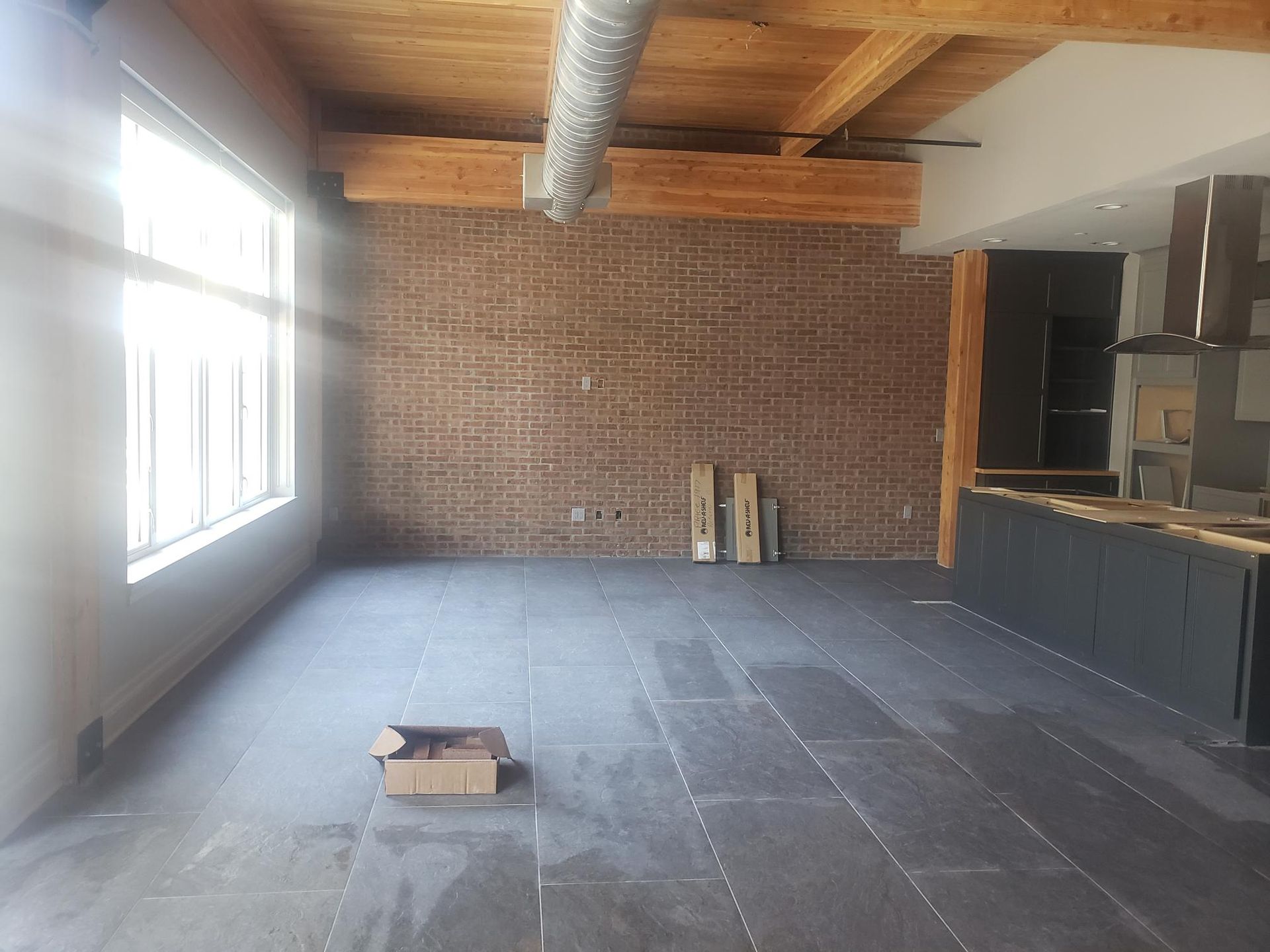 An empty room with a brick wall and a box on the floor